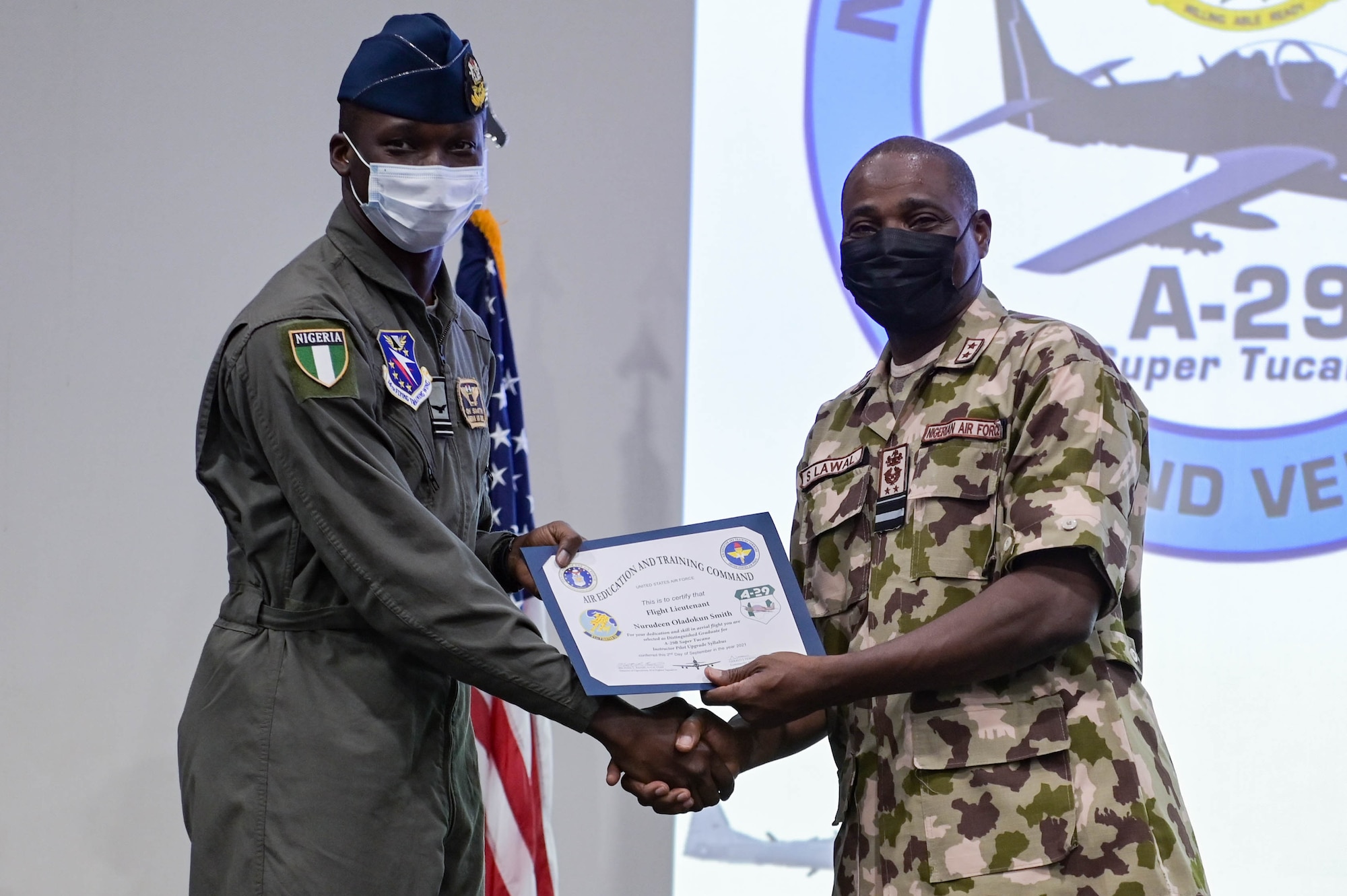 Nigerian Air Force Air Vice Marshal Sule Lawal, Nigerian A-29 program lead foreign liaison officer, right, recognizes Nigerian Air Force A-29 Super Tucano pilot, left, as a distinguished graduate for the instructor upgrade syllabus during the NAF A-29 pilot graduation ceremony at Moody Air Force Base, Georgia, Sept. 2, 2021. In under one year, the NAF pilots became mission ready through their hard work and dedication in their training. (U.S. Air Force photo by Senior Airman Rebeckah Medeiros)