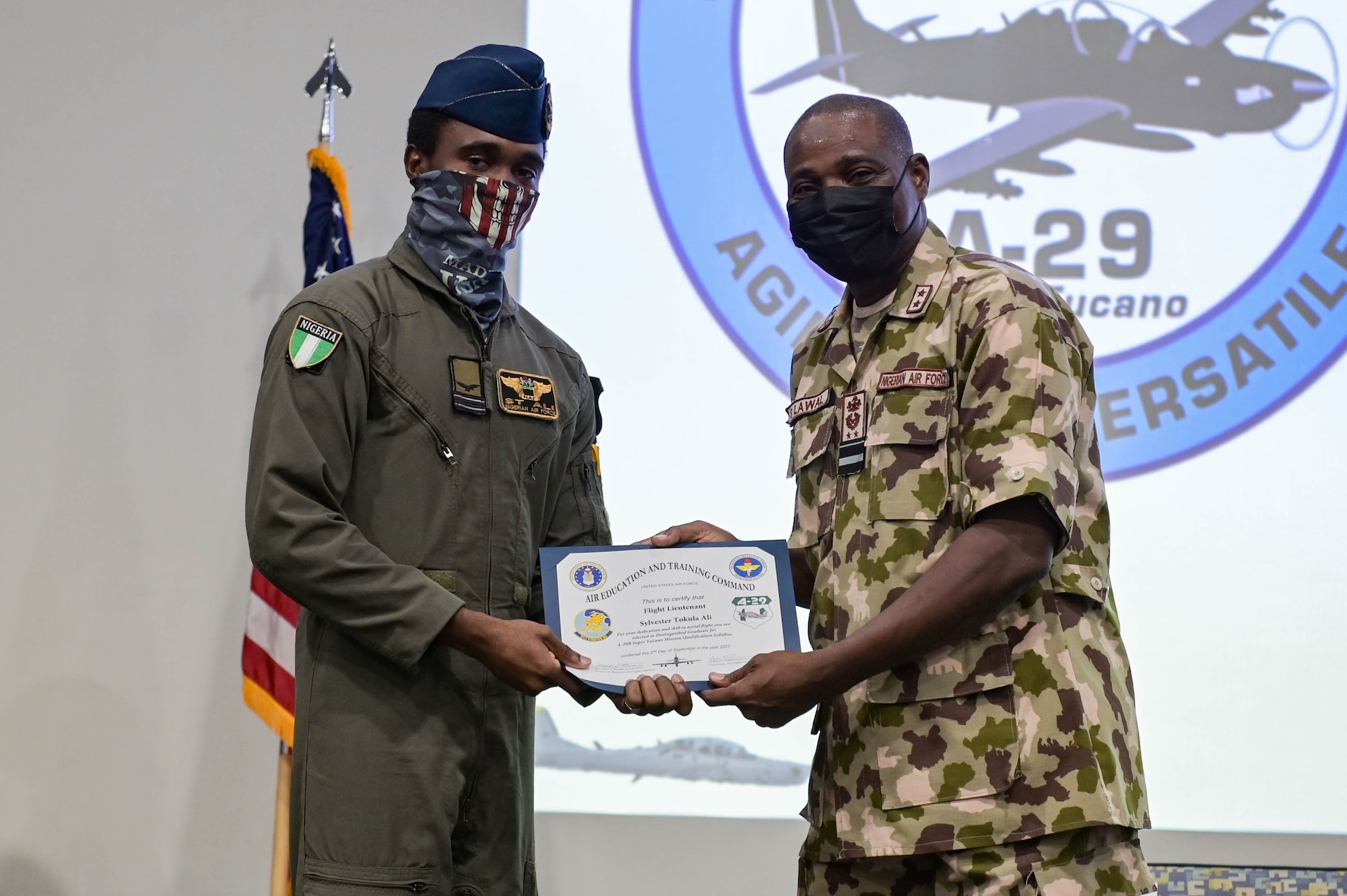 Nigerian Air Force Air Vice Marshal Sule Lawal, Nigerian A-29 program lead foreign liaison officer, right, recognizes Nigerian Air Force A-29 Super Tucano aircraft pilot, left, as a distinguished graduate for the mission qualification syllabus during the NAF A-29 pilot graduation ceremony at Moody Air Force Base, Georgia, Sept. 2, 2021. Upon graduating, the NAF pilots are qualified to strafe with two .50-caliber machine guns, shoot high explosive rockets, and drop both general purpose and laser guided bombs. (U.S. Air Force photo by Senior Airman Rebeckah Medeiros)