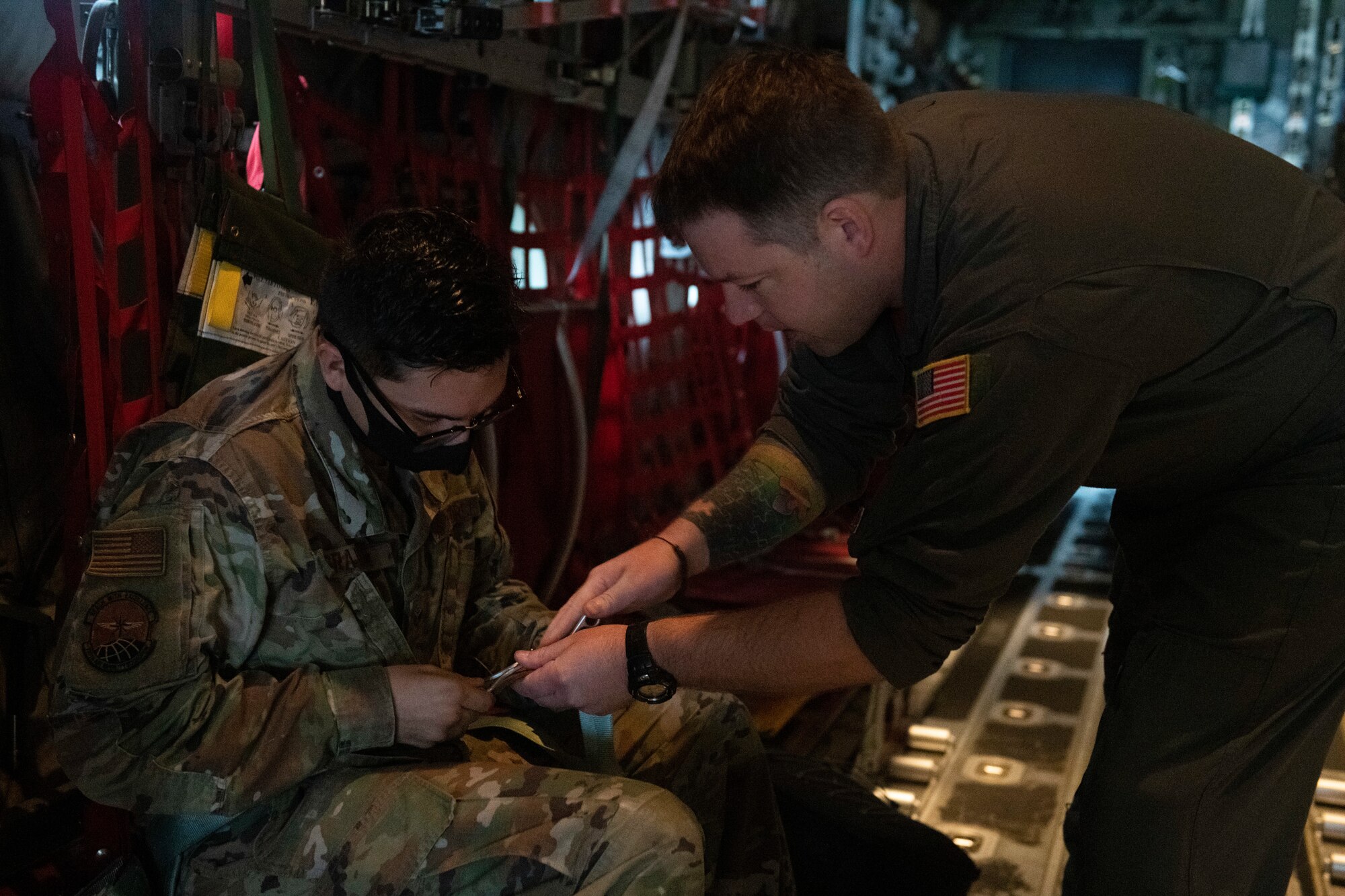 Tech. Sgt. Chad Barnette, 36th Airlift Squadron evaluator loadmaster, right, helps Senior Airman Christian Graves, 730th Air Mobility Squadron fleet technician, with a seatbelt prior to takeoff at Yokota Air Base, Japan, Oct. 1, 2021. Barnette and the other loadmasters ensured the safety of annual and quarterly award winners on flights showcasing the mission Yokota members support day-to-day. (U.S. Air Force photo by Staff Sgt. Joshua Edwards)
