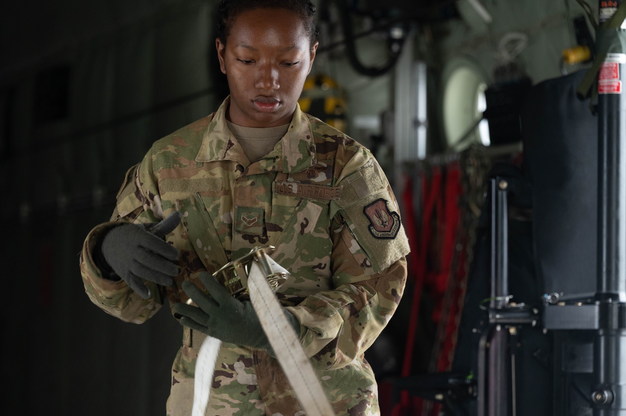 An Airman reels in a 5,000-pound strap.