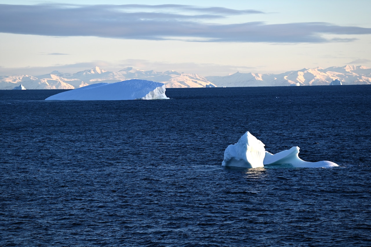 Icebergs poke out of dark blue water.