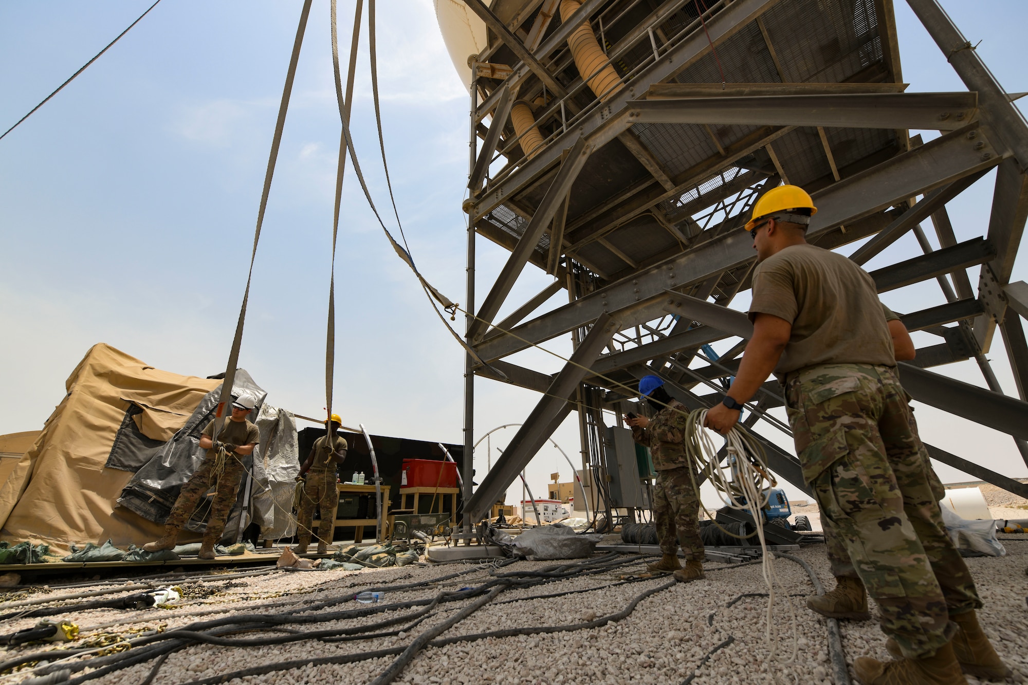 A U.S. Air Force Airman from the 727th Expeditionary Air Control Squadron, Detachment 3, holds a rope to help secure a replacement AN/TPS-75 radar system as it’s lowered into place as part of regular maintenance July 27, 2021, at Al Udeid Air Base, Qatar. 727th EACS radar technicians perform several hours of maintenance and calibration daily to ensure radar systems perform at optimal levels. (U.S. Air Force by Staff Sgt. Alexandria Lee)