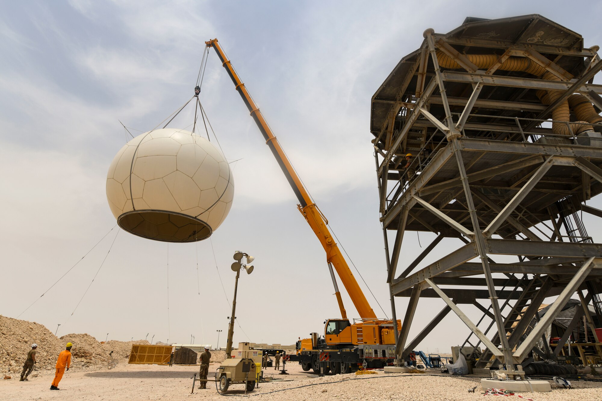 U.S. Air Force Airmen from the 727th Expeditionary Air Control Squadron, Detachment 3, prepare to remove the protective radome covering for an AN/TPS-75 tactical long-range radar system before performing scheduled maintenance July 27, 2021, at Al Udeid Air Base, Qatar. The radar provides a common surveillance and combat identification picture to support battle management command and control for the combined defense of the Arabian Peninsula. (U.S. Air Force by Staff Sgt. Alexandria Lee)