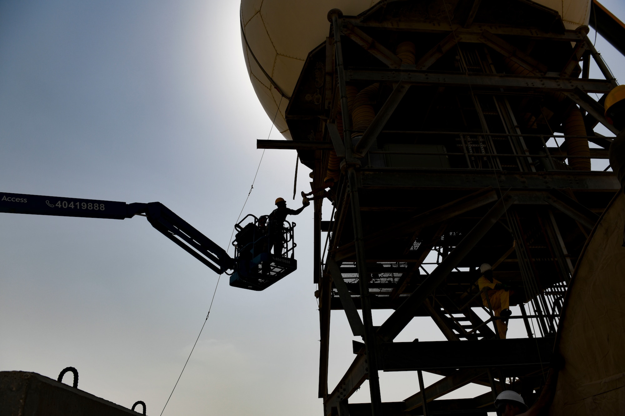 A U.S. Air Force Airman from the 727th Expeditionary Air Control Squadron, Detachment 3, reaches for tools while finishing the final touches on a radome covering for an AN/TPS-75 radar system after routine maintenance July 27, 2021, at Al Udeid Air Base, Qatar. The radome helps ensure longer life cycles for radar systems by providing protection from the elements. (U.S. Air Force by Staff Sgt. Alexandria Lee)