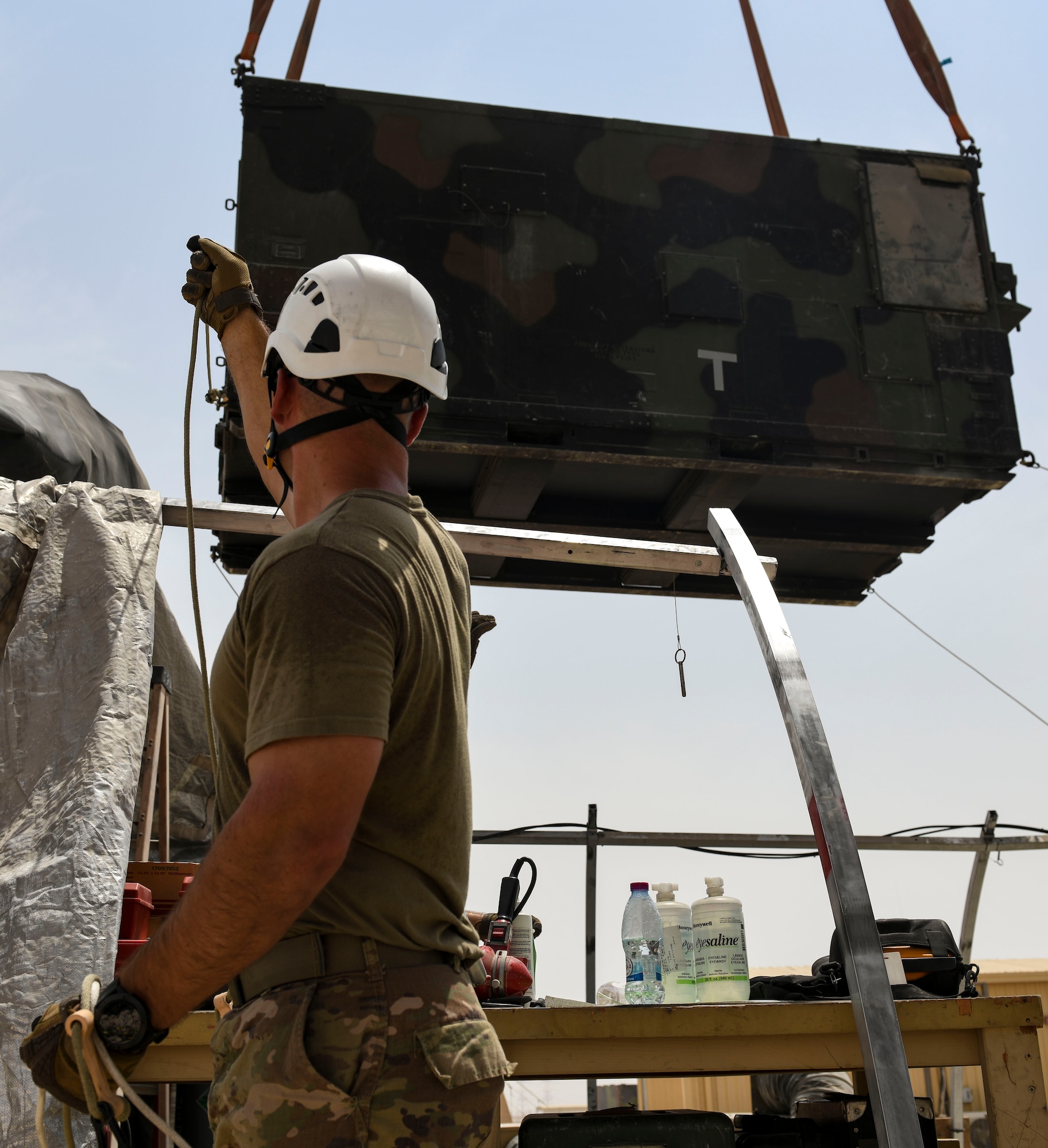 A U.S. Air Force Airman from the 727th Expeditionary Air Control Squadron, Detachment 3, holds a rope to help secure a replacement AN/TPS-75 radar system as it’s lowered into place as part of regular maintenance July 27, 2021, at Al Udeid Air Base, Qatar. 727th EACS radar technicians perform several hours of maintenance and calibration daily to ensure radar systems perform at optimal levels. (U.S. Air Force by Staff Sgt. Alexandria Lee)