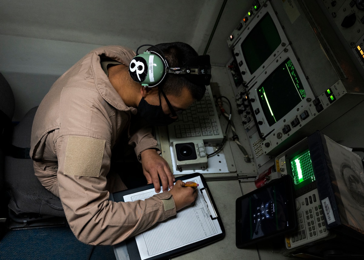 U.S. Air Force Senior Airman Nicolas Queiroz, 968th Expeditionary Airborne Air Control Squadron E-3 Sentry airborne radar technician, writes down radar data while flying in an E-3 over Southwest Asia, March 12, 2021. Radar technicians are responsible for the maintenance and upkeep of all radar equipment to ensure technology on board the E-3 can gather and present broad and detailed battlefield information. (U.S. Air Force photo by Senior Airman Bryan Guthrie)