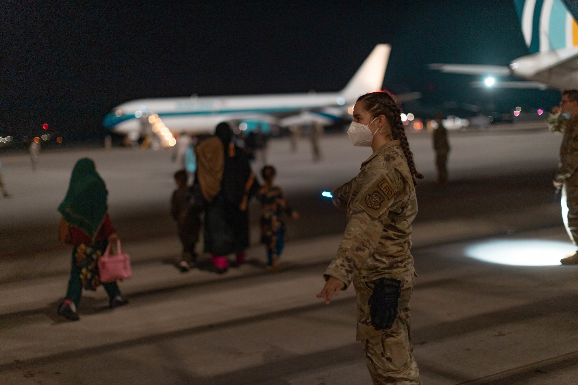 Capt. Cassandra Hill directs Afghan travelers to their awaiting aircraft at Ramstein Air Base, Germany