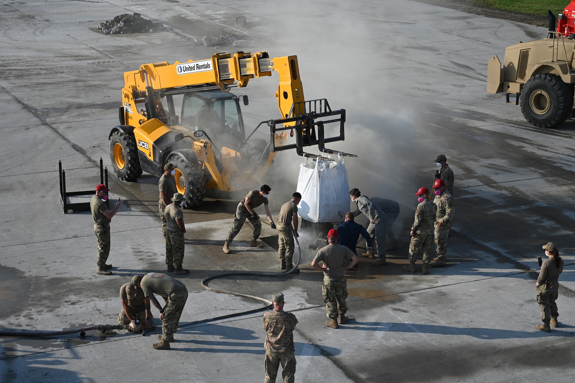 Many military members can be seen in this view from above as they rake fast-drying concrete material into place in a hole on a concrete training runway as a teleextender holds a bag in place above the hole at the North Dakota Air National Guard Regional Training Site, Fargo, N.D., Sept, 30, 2021.