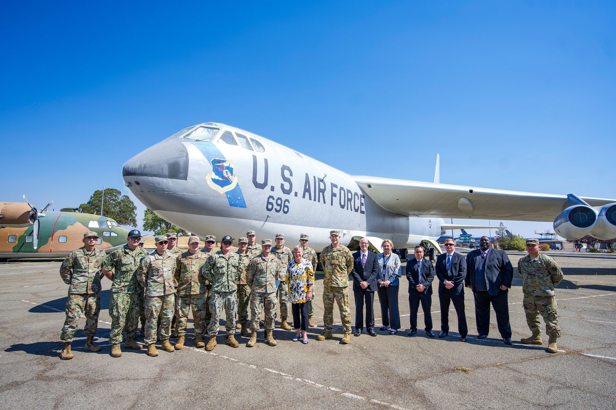 A group of service members pose for a photo on a sunny day in front of a B-52