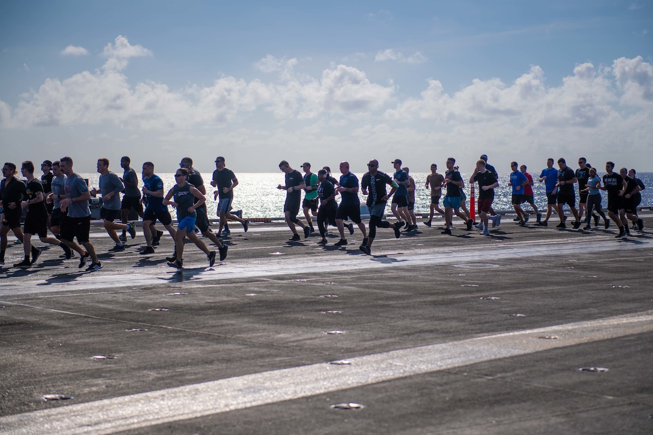 Sailors run on the flight deck of an aircraft carrier.