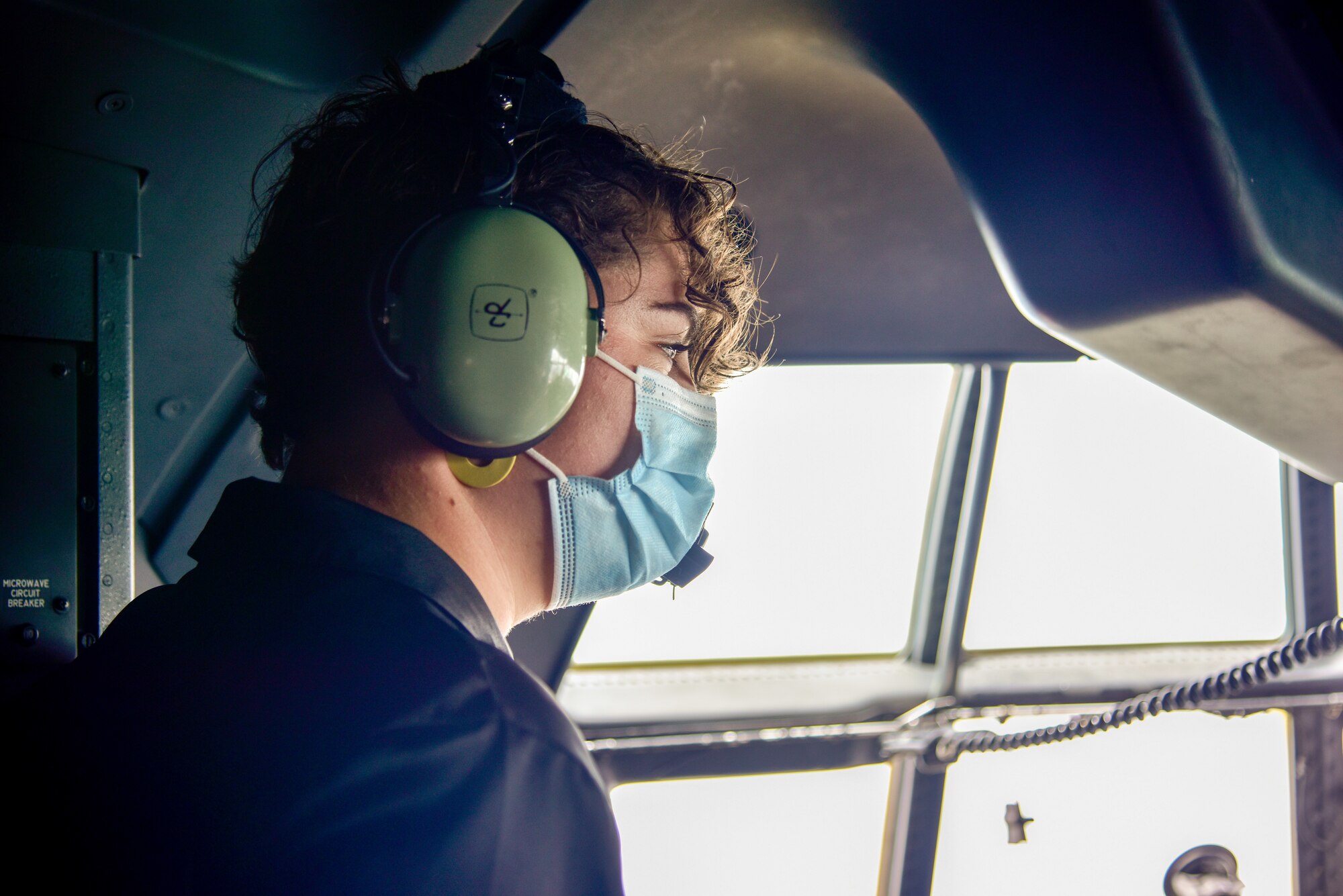 A person looks out the window of a C-130J