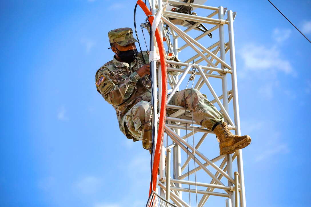 A soldier climbs a communication tower.
