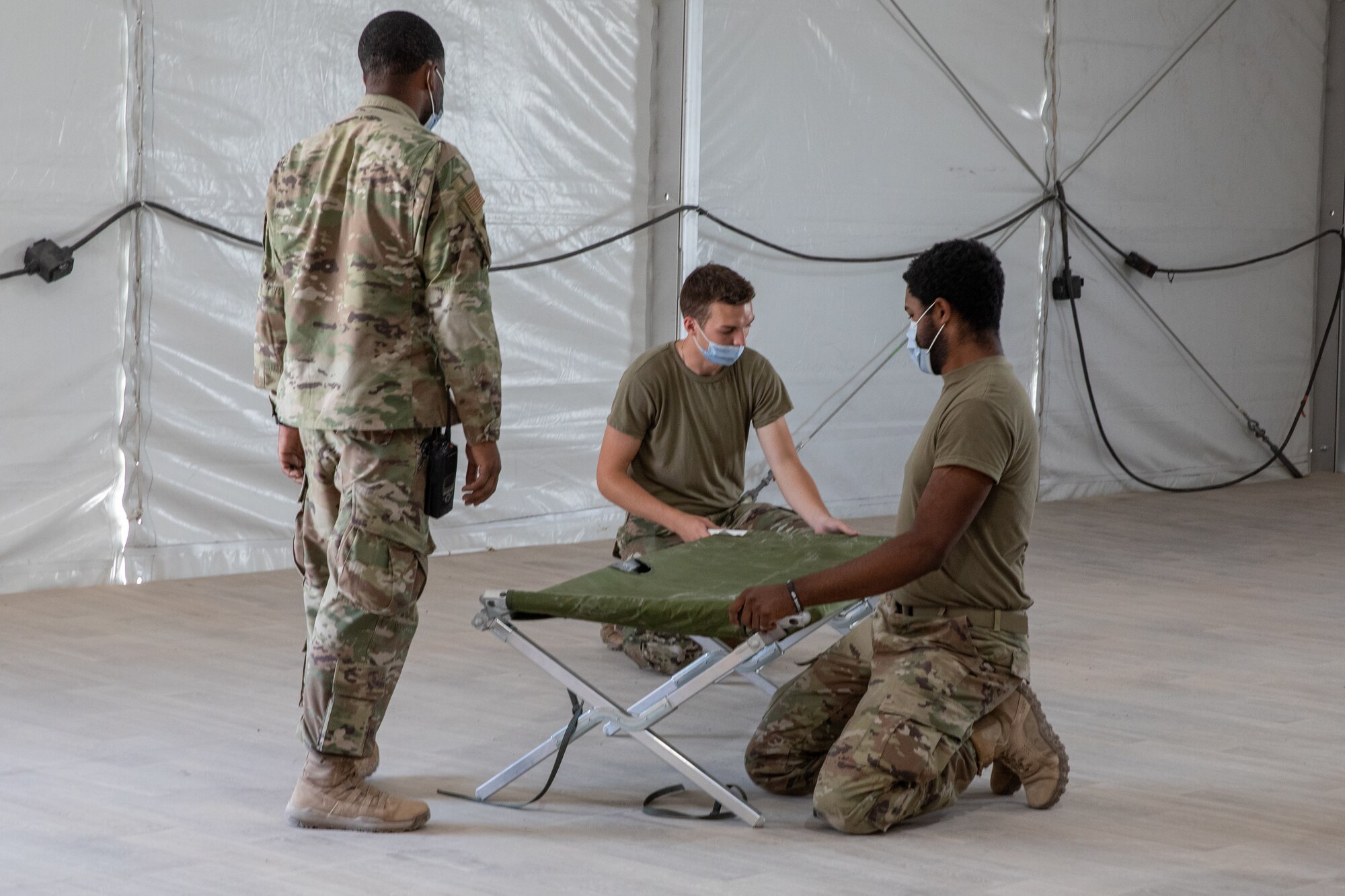 Task Force-Holloman Airmen assemble cots in a new triage tent at Aman Omid Village on Holloman Air Force Base, New Mexico, Sept. 22, 2021. The Department of Defense, through the U.S. Northern Command, and in support of the Department of State and Department of Homeland Security, is providing transportation, temporary housing, medical screening, and general support for at least 50,000 Afghan evacuees at suitable facilities, in permanent or temporary structures, as quickly as possible. This initiative provides Afghan evacuees essential support at secure locations outside Afghanistan. (U.S. Army photo by Spc. Nicholas Goodman)