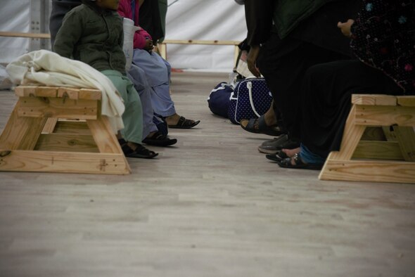 Afghan families wait patiently during out processing before, heading to the airport where they will fly to their new homes in America, on Holloman Air Force Base, New Mexico, Sept. 30, 2021. The Department of Defense, through U.S. Northern Command, and in support of the Department of State and Department of Homeland Security, is providing transportation, temporary housing, medical screening, and general support for at least 50,000 Afghan evacuees at suitable facilities, in permanent or temporary structures, as quickly as possible. This initiative provides Afghan evacuees essential support at secure locations outside Afghanistan. (U.S. Navy photo by Mass Communications Specialist 1st Class Sarah Rolin)