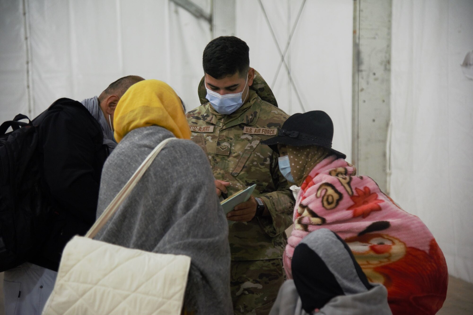 An Airman assigned to Task Force-Holloman assists an Afghan family with final details before they depart Holloman Air Force Base, New Mexico, Sept. 30, 2021. The Department of Defense, through U.S. Northern Command, and in support of the Department of State and Department of Homeland Security, is providing transportation, temporary housing, medical screening, and general support for at least 50,000 Afghan evacuees at suitable facilities, in permanent or temporary structures, as quickly as possible. This initiative provides Afghan evacuees essential support at secure locations outside Afghanistan. (U.S. Navy photo by Mass Communications Specialist 1st Class Sarah Rolin)