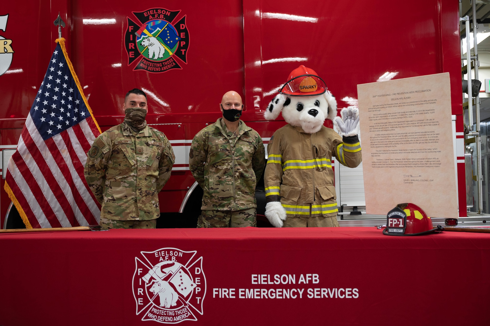 From left to right, U.S. Air Force Master Sgt. Christopher Brown, the 354th Civil Engineering Squadron deputy fire chief, Col. David Berkland, the 354th Fighter Wing commander, and Sparky the fire dog pose for a group photo during the fire prevention week proclamation signing on Eielson Air Force Base, Alaska, Sept. 17, 2021.