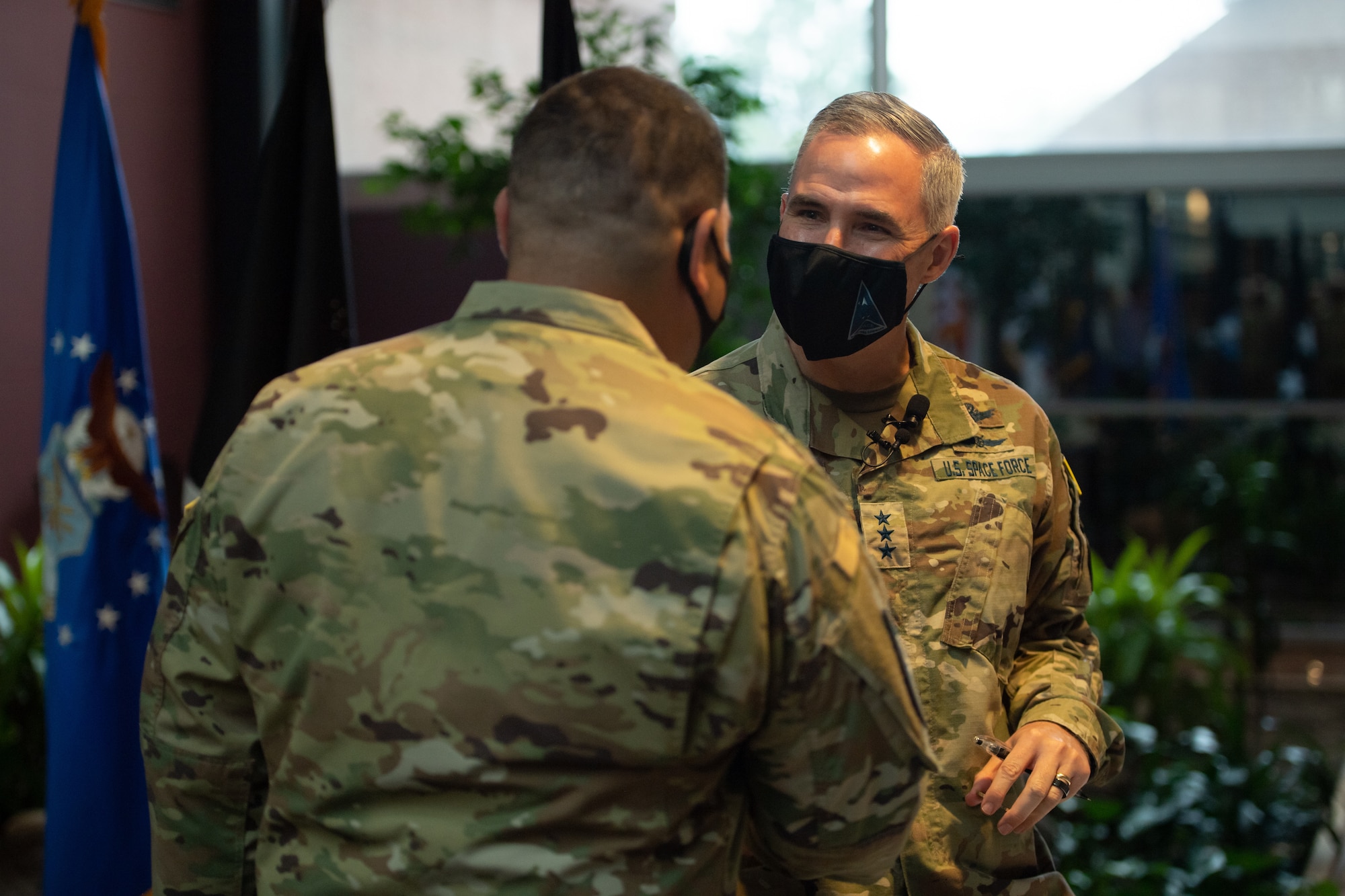 Lt. Gen. Stephen Whiting, Space Operations Command commander, shakes hands with Senior Master Sgt. Raymond Flores after officially inducting him into the U.S. Space Force Oct. 1, 2021, at Peterson Space Force Base, Colorado.