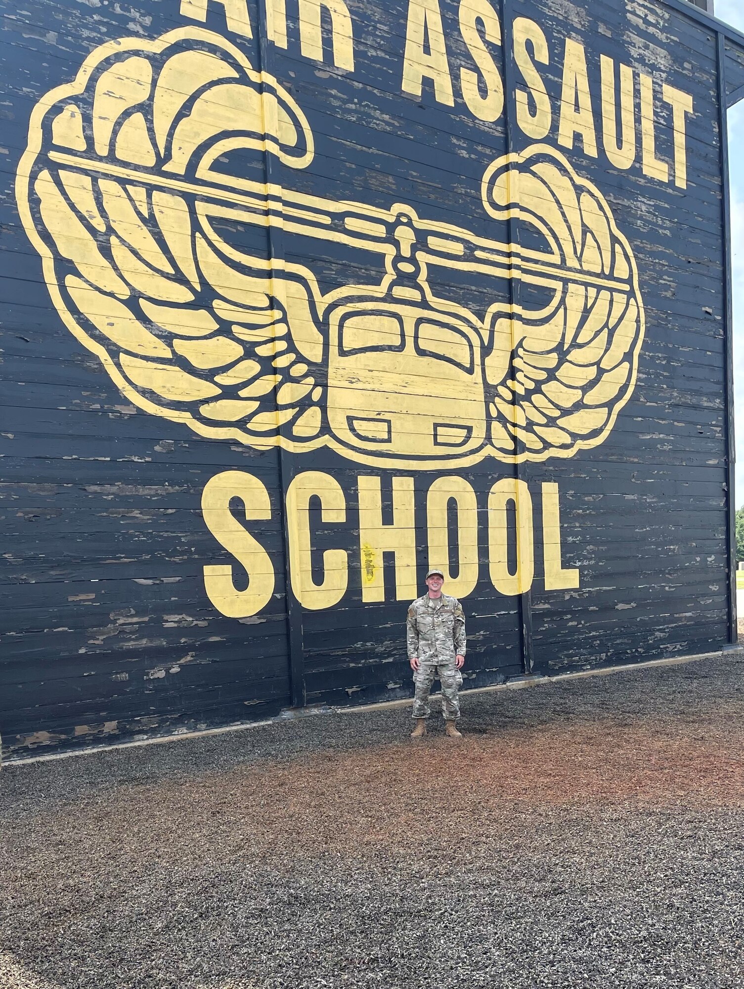 A photo of an Airman standing in front of the Army Air Assault School sign