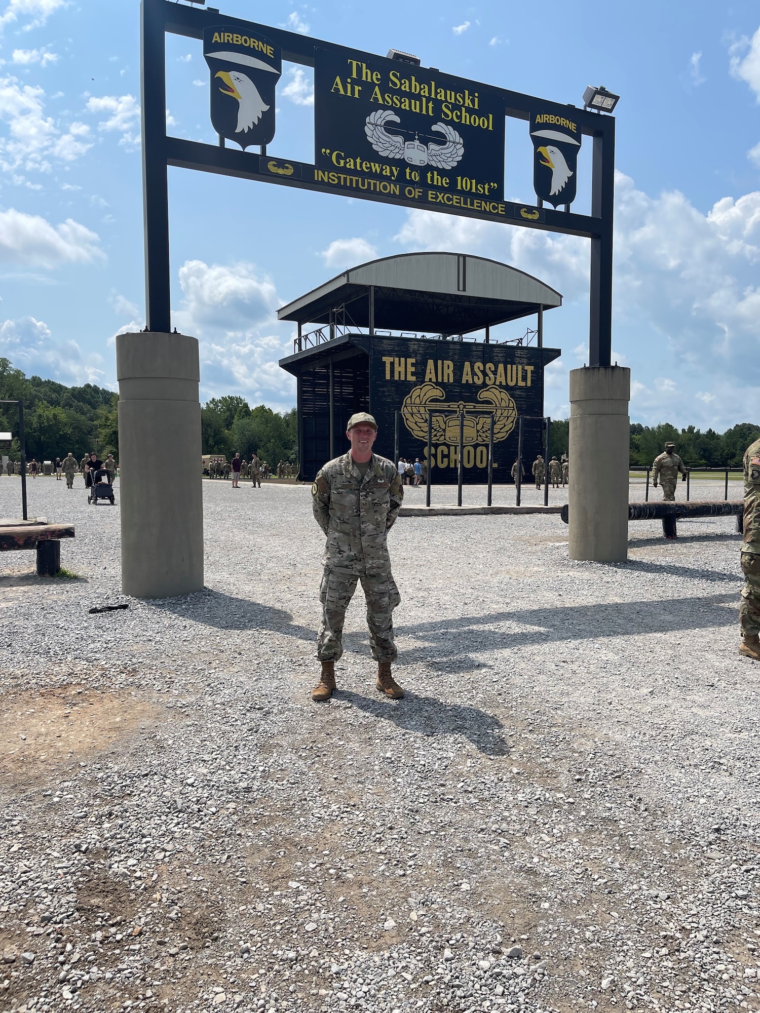 A photo of an Airman standing in front of the Army Air Assault School sign