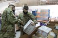 Spc. Matthew A. Hernandez, a Soldier assigned to 678th Human Resources Company, scans a package held by Cpl. Brett D. Ellis, a human resources specialist assigned to the Fort Bragg, North Carolina, based Headquarters and Headquarters Company, 3rd Expeditionary Sustainment Command, at the post office on Camp Arifjan, Kuwait, on Oct. 2, 2021. Ellis, a native of Fort Worth, Texas, is one of many Soldiers deployed to Kuwait staffing the 1st Theater Sustainment Command Operational Command Post.
