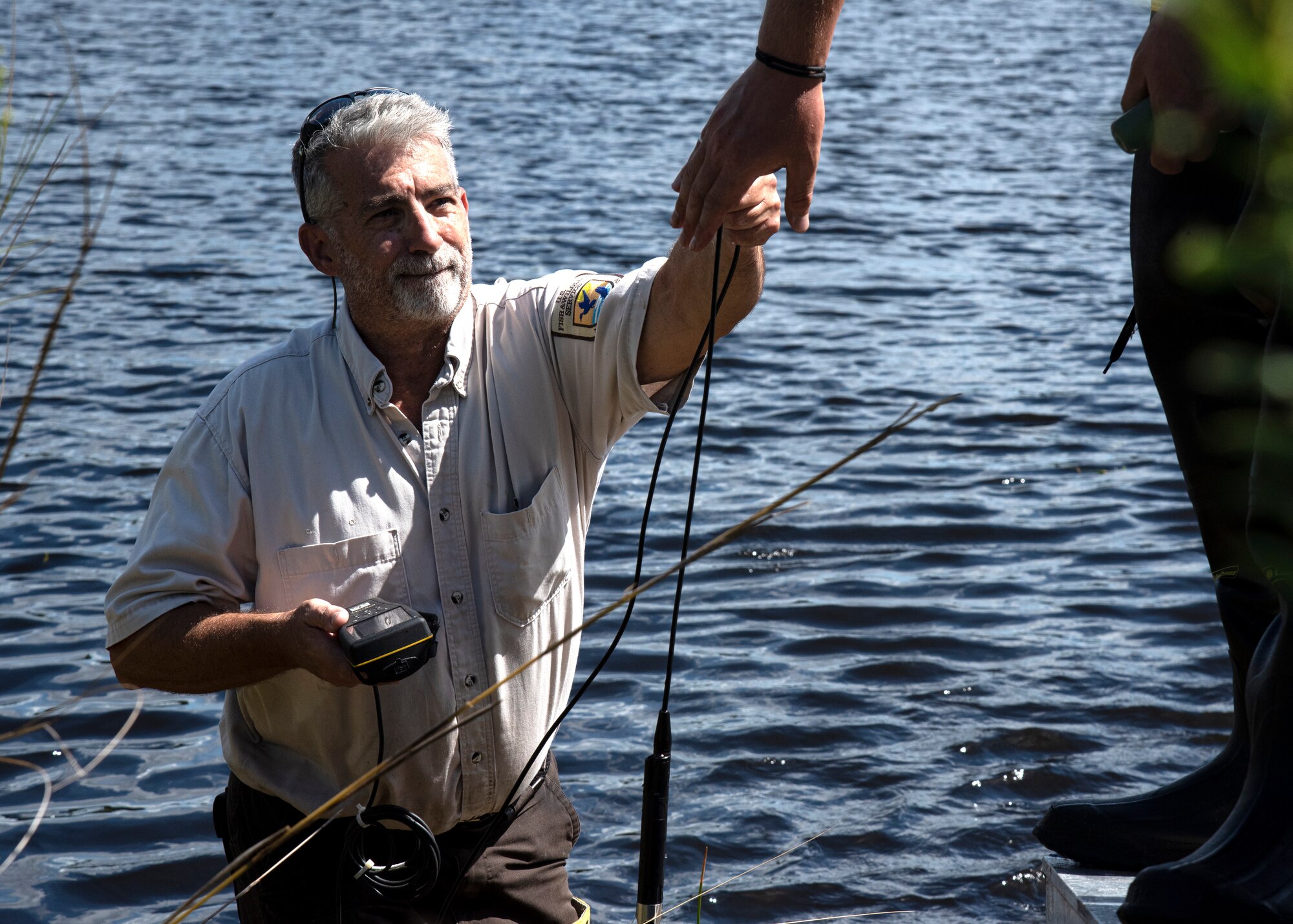 Ken Blick, the Welaka National Fish Hatchery project leader, hands off a ProSolo Digital Water Quality Meter at Lewis Lake on MacDill Air Force Base, Florida, Oct. 1, 2021.