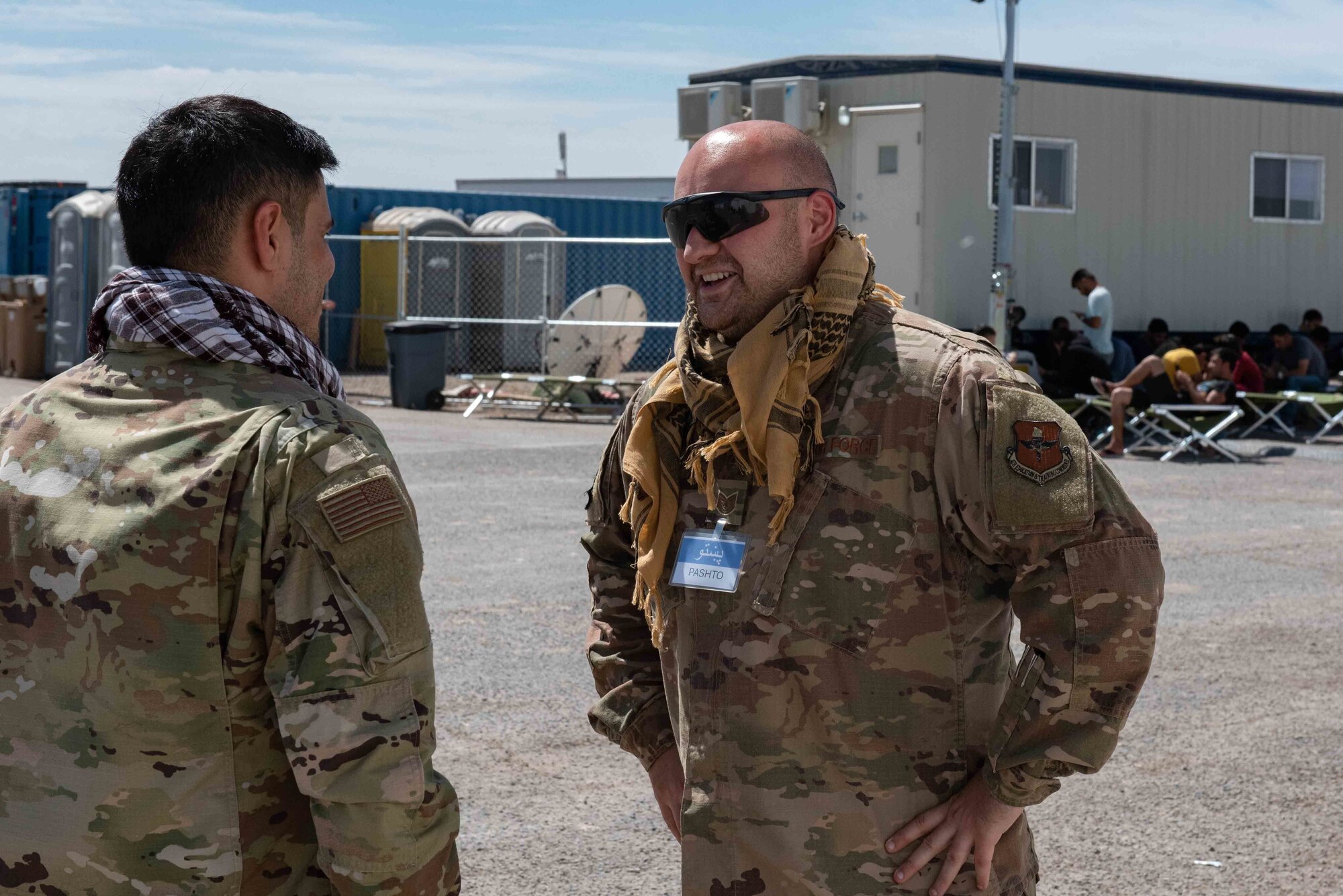 Tech. Sgt. Steven Toma, Task Force-Holloman interpreter deployed from Goodfellow Air Force Base, Texas, speaks with another TF-H interpreter at Aman Omid Village on Holloman Air Force Base, New Mexico, Sept. 23, 2021. The Department of Defense, through U.S. Northern Command, and in support of the Department of State and Department of Homeland Security, is providing transportation, temporary housing, medical screening, and general support for at least 50,000 Afghan evacuees at suitable facilities, in permanent or temporary structures, as quickly as possible. This initiative provides Afghan evacuees essential support at secure locations outside Afghanistan. (U.S. Air Force photo by Staff Sgt. Kenneth Boyton)