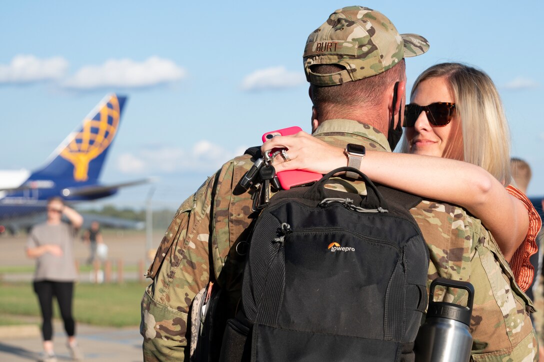 A man in uniform and woman hug.