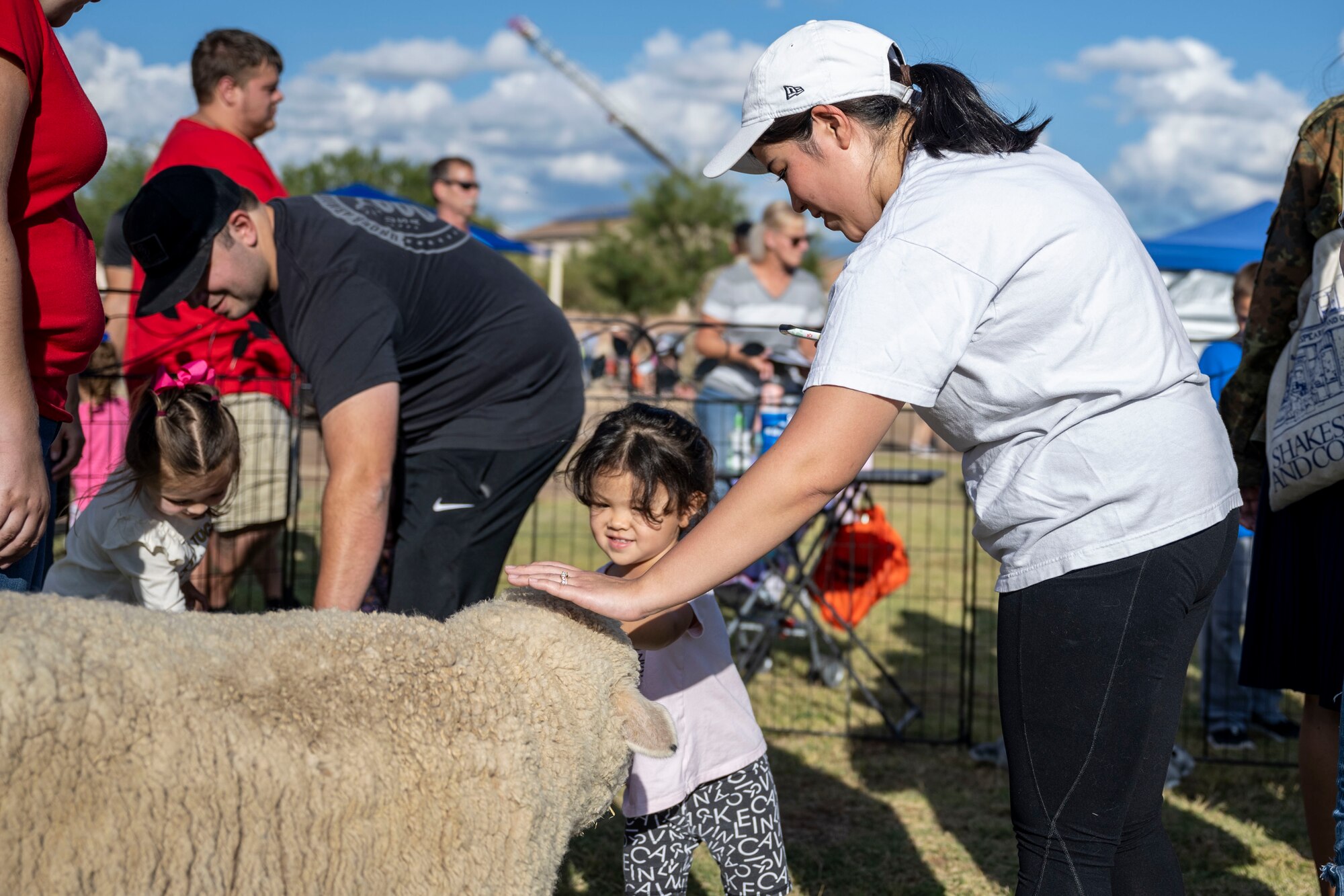 Mia and Sachiko Baudo, Soaring Heights residents, pet a sheep in the petting zoo Oct. 1, 2021 on Holloman Air Force Base, N.M. National Night Out offered individuals with base access a variety of activities to participate in including free food, a bounce house and various displays of local and 49th Wing law enforcement and first responders. (U.S. Air Force photo by Senior Airman Kristin Weathersby)