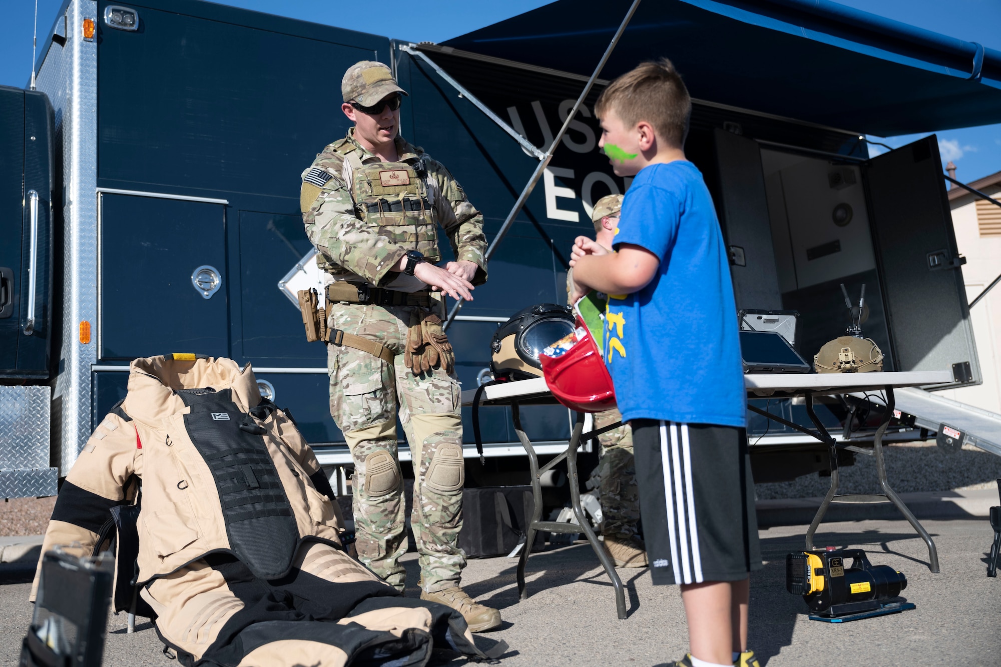 Technical Sgt. Jacob Bellack, 49th Civil Engineer Squadron explosive ordnance disposal team leader, explains the purpose of the bomb suit to a Holloman resident Oct. 1, 2021 on Holloman Air Force Base, N.M. The EOD flight showcased the EOD robot, inactive shells and other equipment to inform attendants of their job duties. (U.S. Air Force photo by Senior Airman Kristin Weathersby)