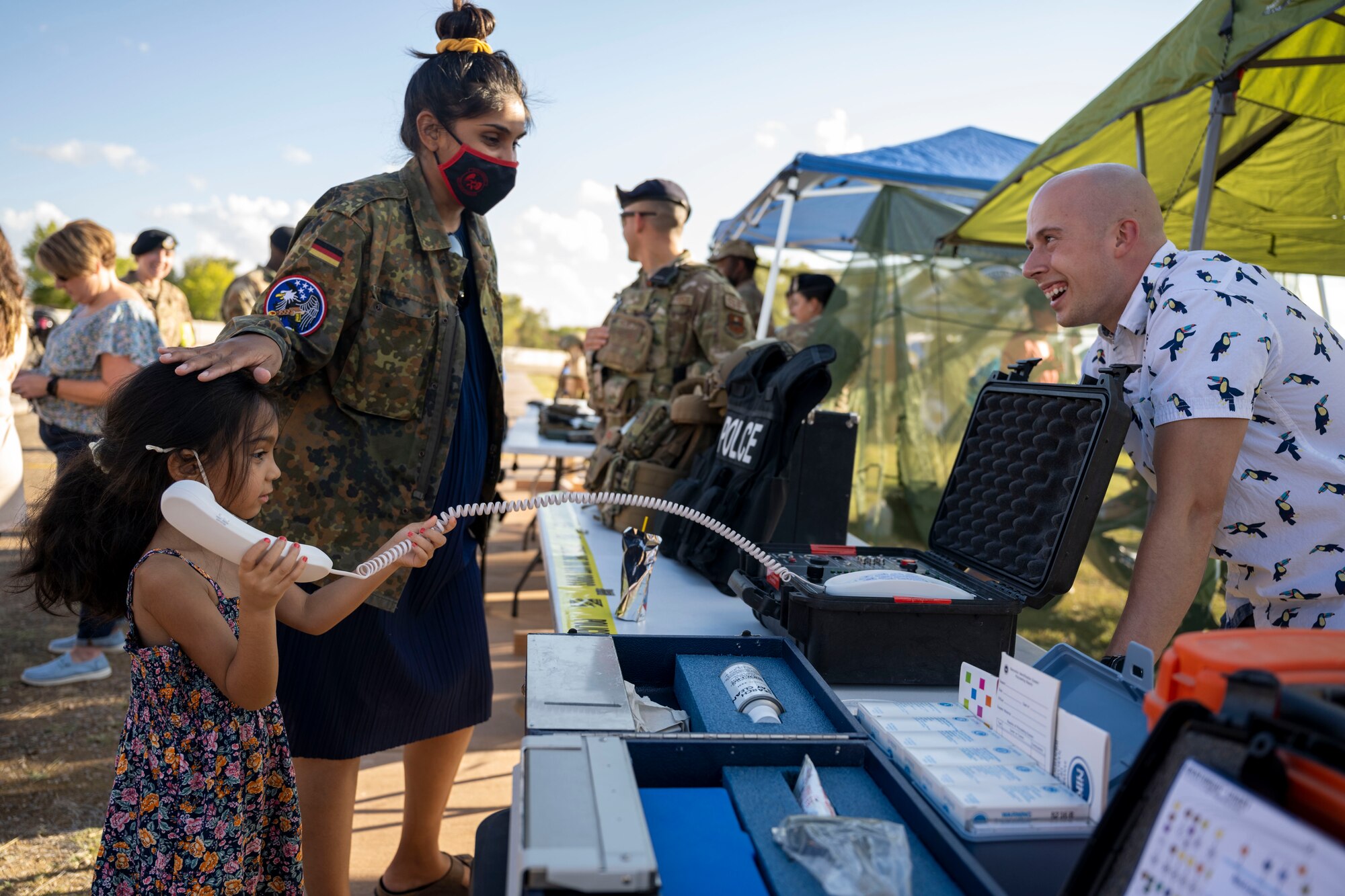 Investigator Timothy Bell, 49th Security Forces Squadron investigator, shows Ameilia and Sarah Knowles, Soaring Heights residents, a crisis negotiations phone that was once used by the 49th SFS crisis negotiations team Oct. 1, 2021 on Holloman Air Force Base, N.M. The 49th SFS booth had information on the different flights within the squadron. (U.S. Air Force photo by Senior Airman Kristin Weathersby)