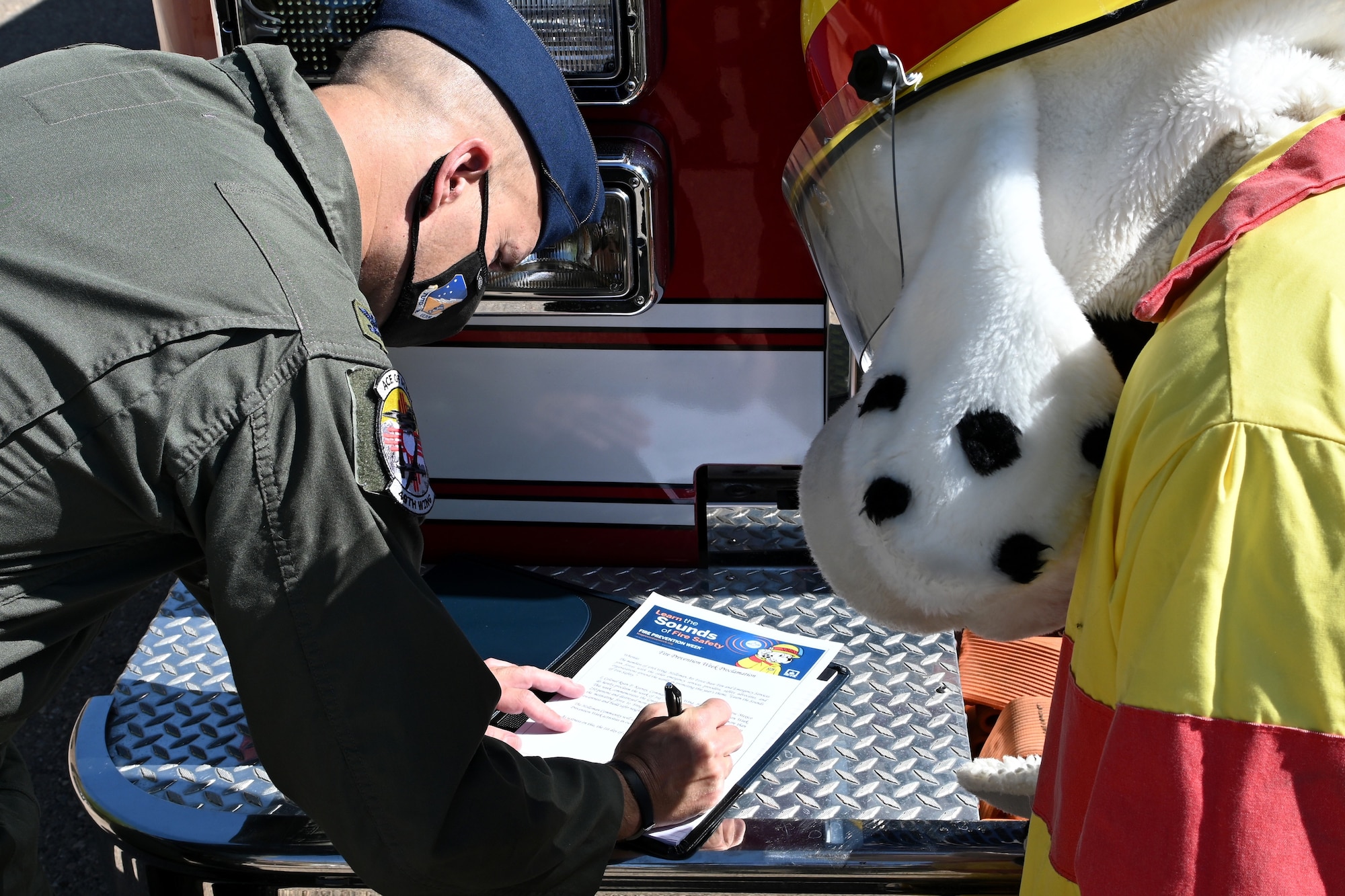 Col. Ryan Keeney, 49th Wing commander, signs the 2021 Fire Prevention Week proclamation with the National Fire Protection Association mascot ‘Sparky the Fire Dog’ Oct. 1, 2021 on Holloman Air Force Base, New Mexico. Fire Prevention Week is the longest running public health observance in the United States and pays homage to the Great Chicago Fire of 1871. (U.S. Air Force photo by Staff Sgt. Christopher Sparks)
