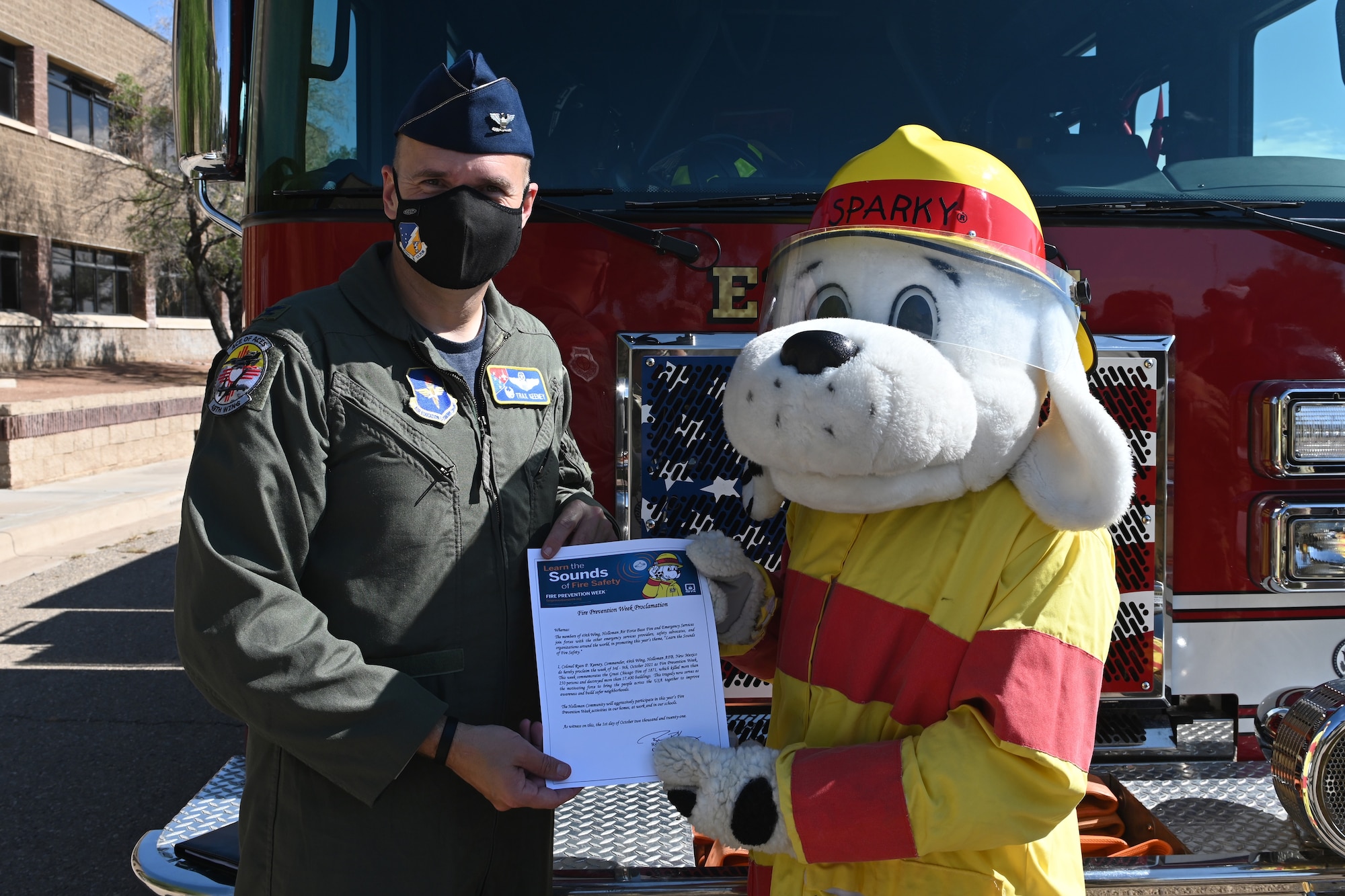 Col. Ryan Keeney, 49th Wing commander, holds the 2021 Fire Prevention Week proclamation with the National Fire Protection Association mascot ‘Sparky the Fire Dog’ Oct. 1, 2021 on Holloman Air Force Base, New Mexico. Fire Prevention Week has taken place the week of Oct. 9 since former president Calvin Coolidge proclaimed it a national observance in 1925. (U.S. Air Force photo by Staff Sgt. Christopher Sparks)