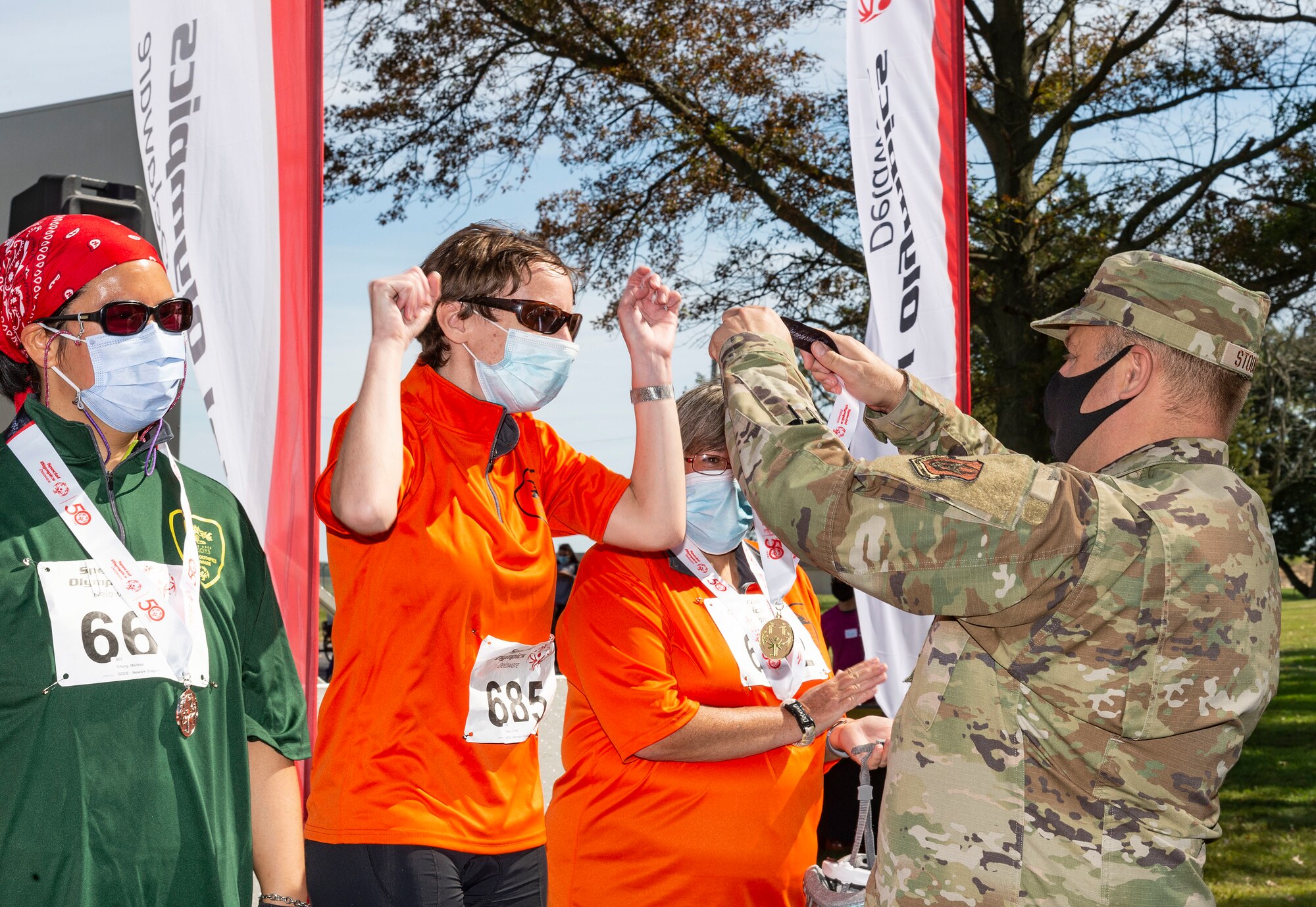 Col. Douglas Stouffer, 512th Airlift Wing commander, right, places a gold medal on Christi Theron at the 2021 Special Olympics Delaware Cycling Classic at Dover Air Force Base, Delaware, Oct. 2, 2021. Theron won gold in the 5K, Division 505 bicycle race. (U.S. Air Force photo by Roland Balik)