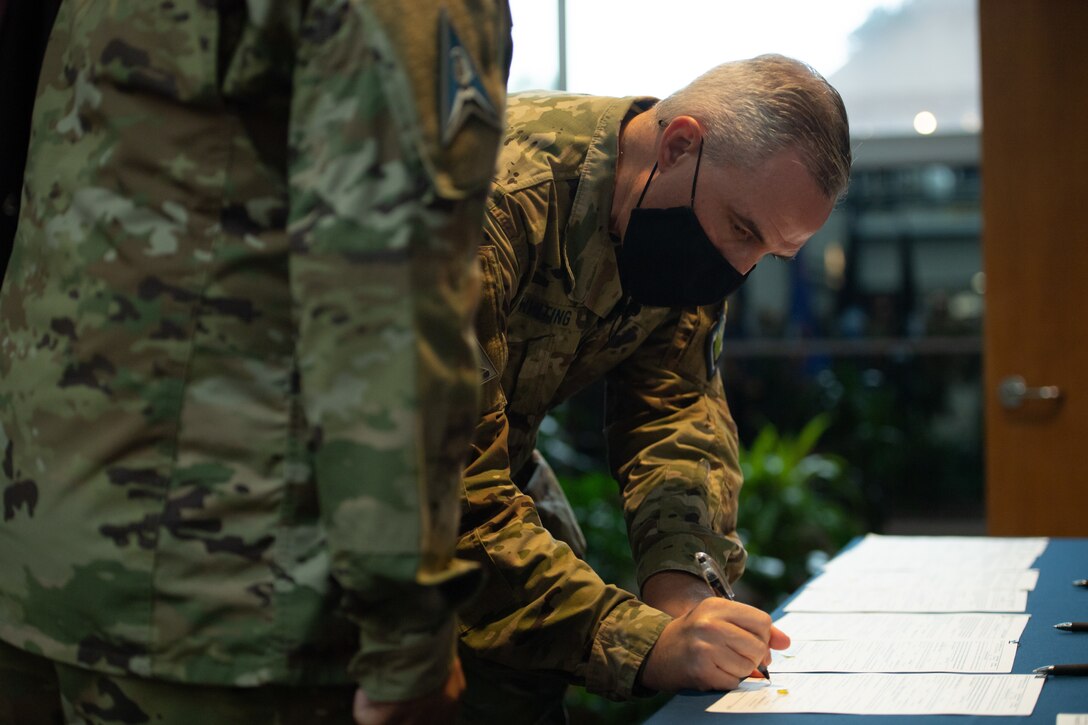 Lt. Gen. Stephen Whiting, Space Operations Command commander, signs Senior Master Sgt. Raymond Flores’ transfer paperwork, officially inducting him into the U.S. Space Force Oct. 1, 2021, at Peterson Space Force Base, Colorado.