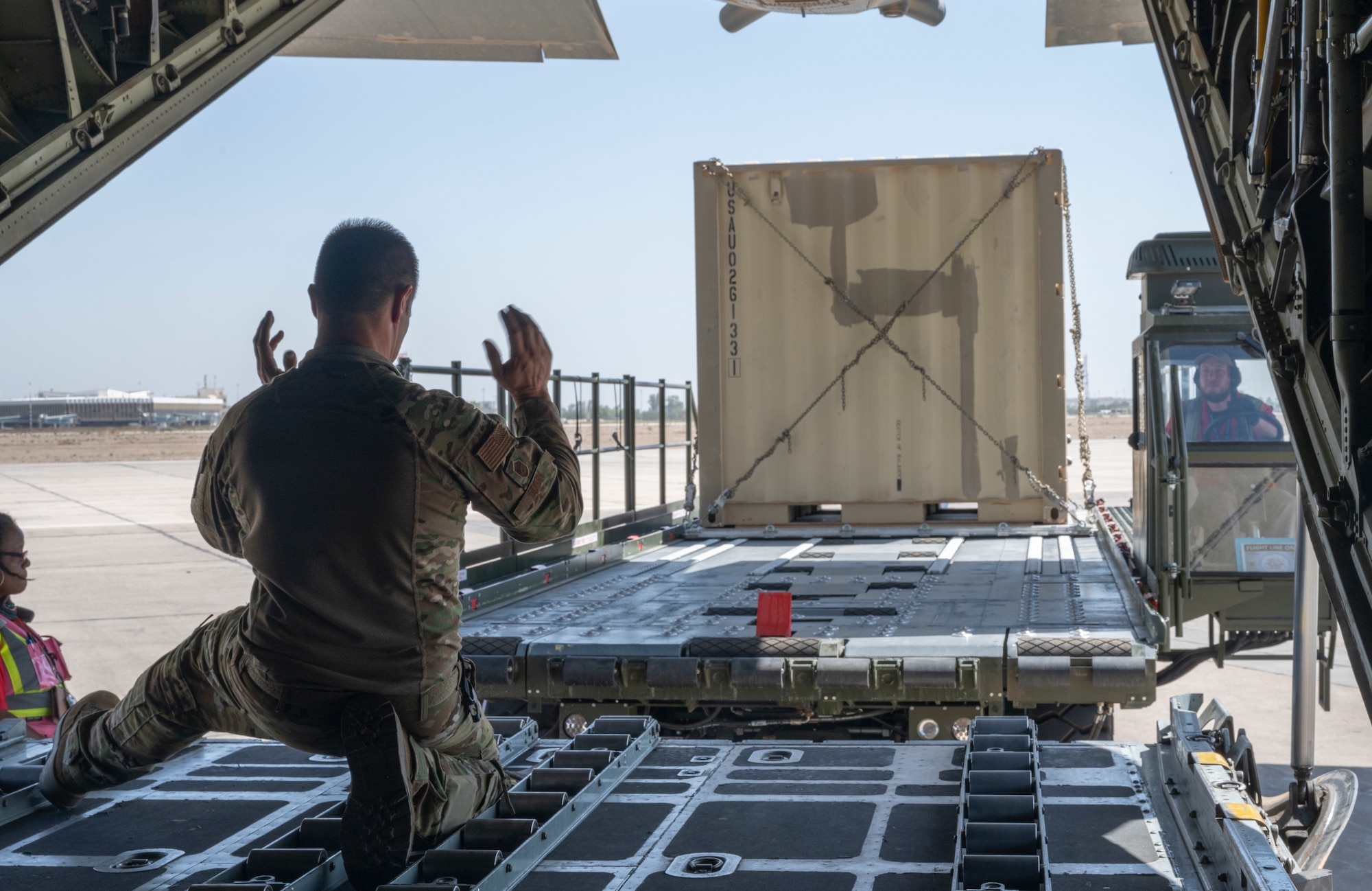 Senior Master Sgt. Mickey Dixon, a loadmaster with the 779th Expeditionary Airlift Squadron, guides a K-Loader carrying cargo towards a C-130H Hercules in Iraq, Sept. 16, 2021.