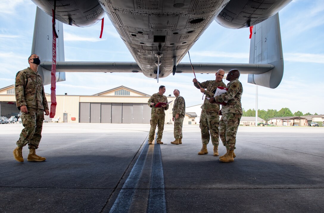 A photo of Airmen standing under aircraft.