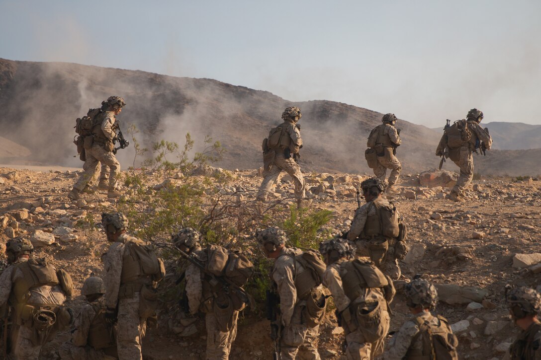 Marines line up to run across a desert landscape.