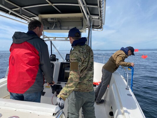 Dr. Alexis Catsambis prepares to drop marker buoys over the wreck site while Dr. George Schwarz and Charles Buffum navigate to the magnetometer targets.