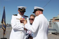 211001-N-HN101-1156 – (NORFOLK, VA) Navy Cyber Defense Operations Command (NCDOC)’s Chief Warrant Officer Four  Jonathan “Jon” Brindle and his wife, watch a recorded video of their son, Airmen Dalton Brindle, deployed on the USS Carl Vinson, reciting "The Watch" during a retirement ceremony on the USS Wisconsin, Oct. 1. (Photo by Rebecca Siders/U.S. Navy photo released)