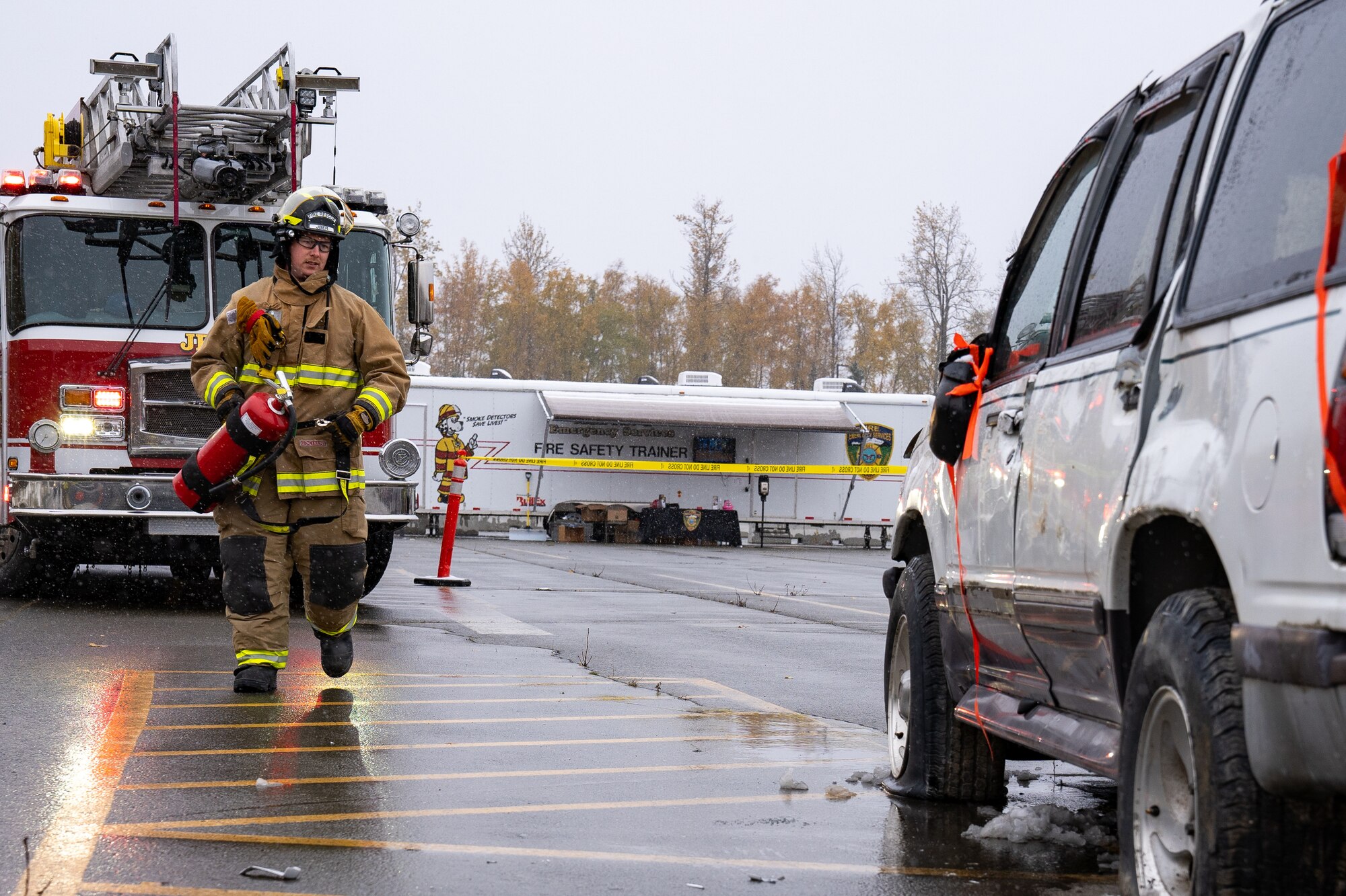 Senior Airman Marcus Davidson, a 673d Civil Engineer Squadron firefighter, approaches a damaged car to perform a vehicle-extrication demonstration during Fire Prevention Day.