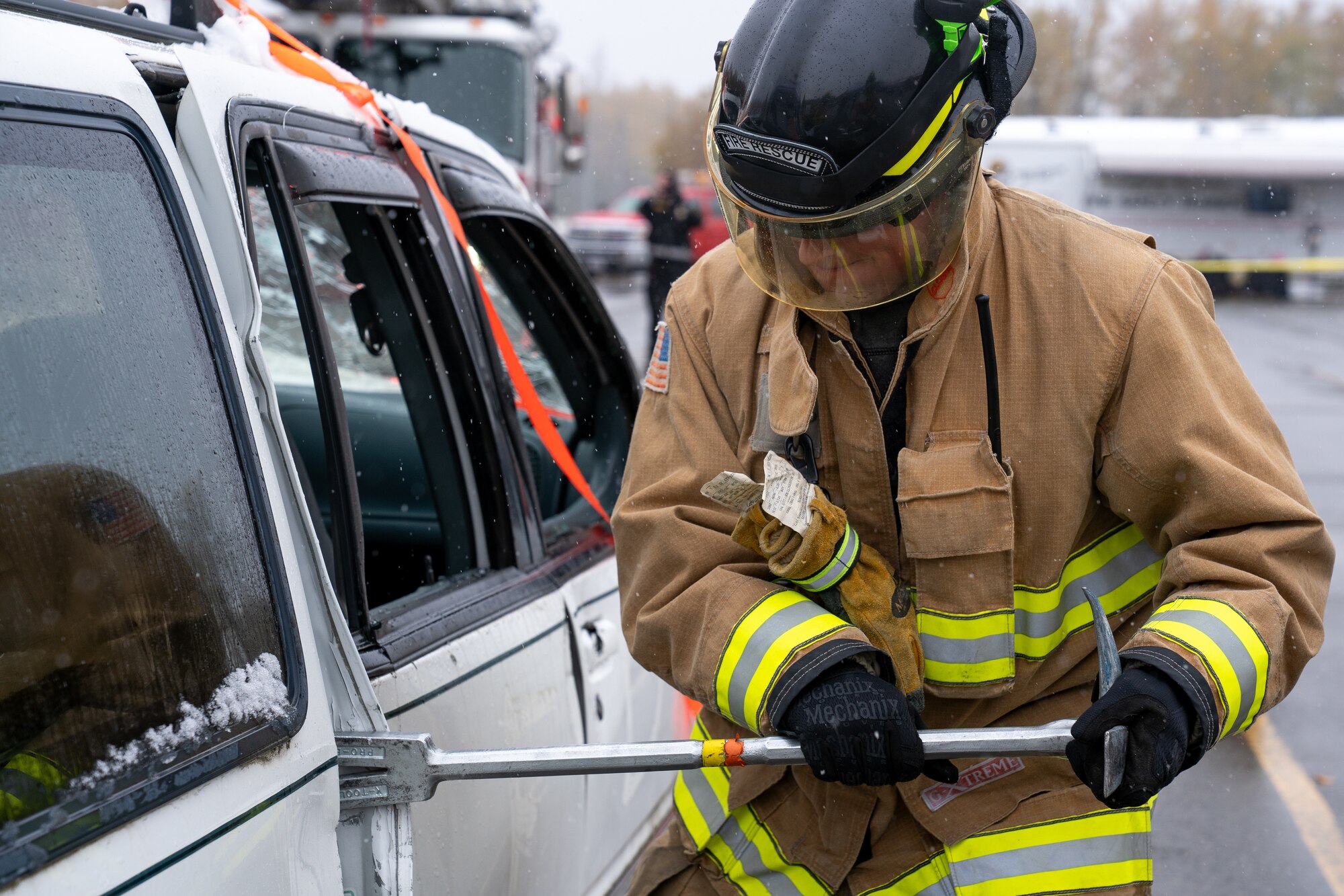 A firefighter assigned to the 673d Civil Engineer Squadron pries the door off of a damaged car for a vehicle-extrication demonstration during Fire Prevention Day.
