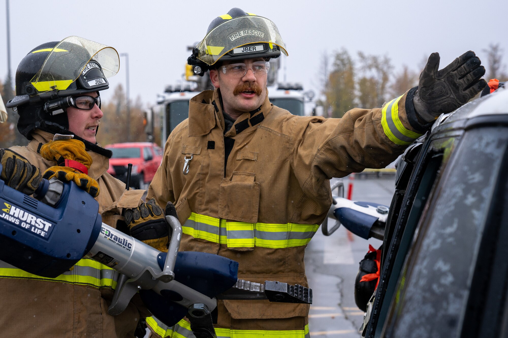 Senior Airman Marcus Davidson and Nicholas Parks, both 673d Civil Engineer Squadron firefighters, prepare to use the Jaws of Life on a damaged car for a vehicle-extrication demonstration during Fire Prevention Day.