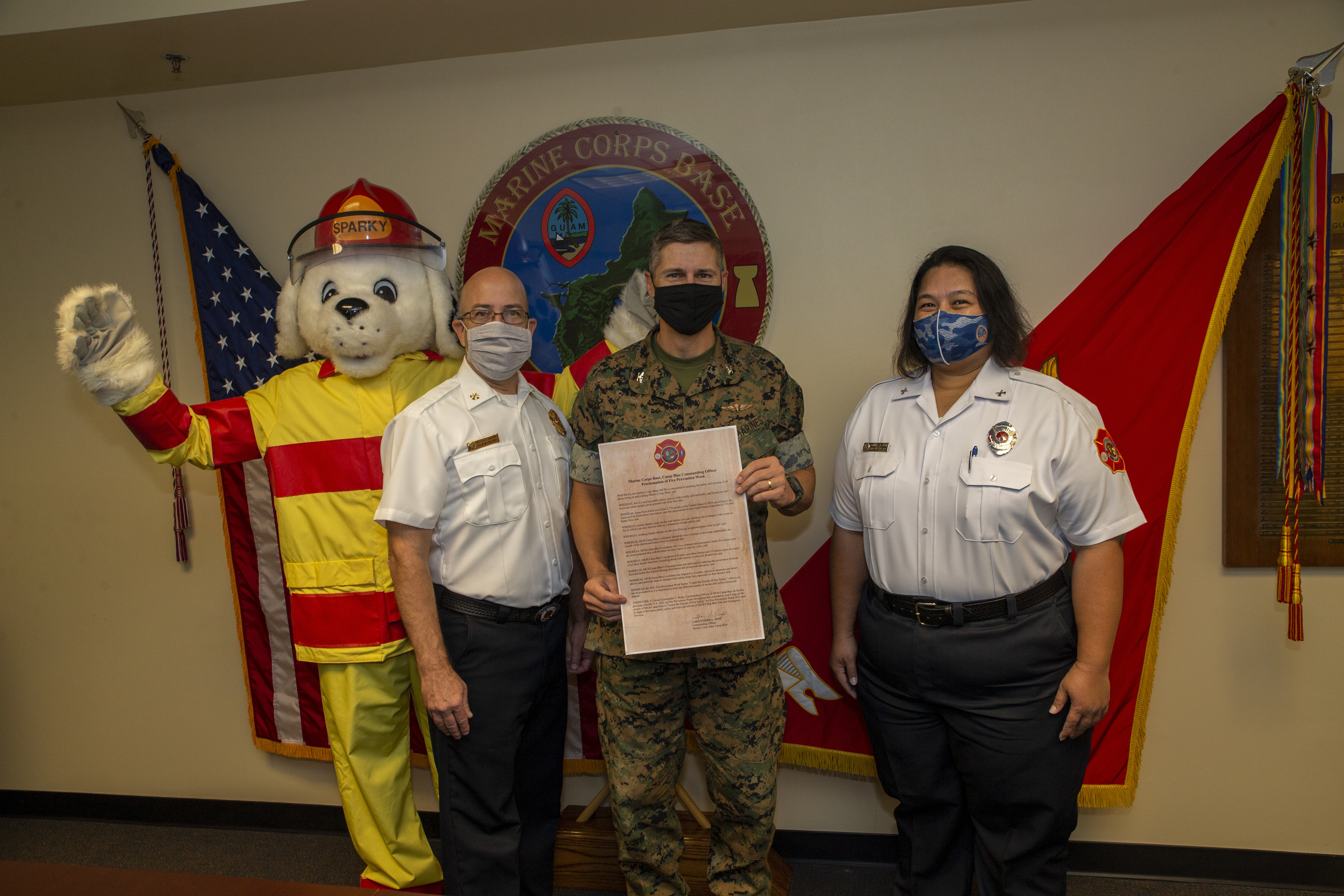 U.S. Marine Corps Col. Christopher Bopp, the Marine Corps Base (MCB) Camp Blaz commanding officer, poses for a photo with Sparky the Fire Dog and members of the MCB Camp Blaz Fire Department after signing a proclamation kicking off Fire Prevention Week aboard the base, Sept. 30, 2021.