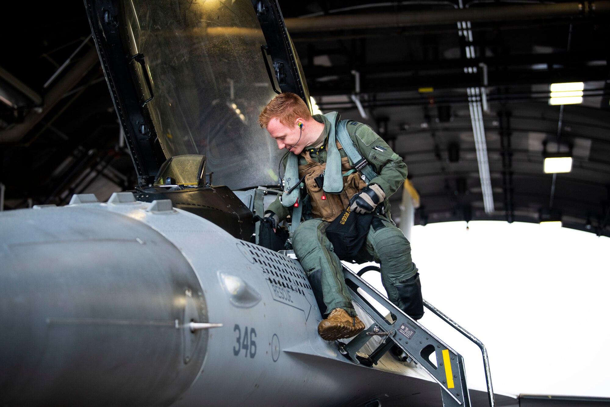 Pilot climbing into the cockpit of a fighter jet.