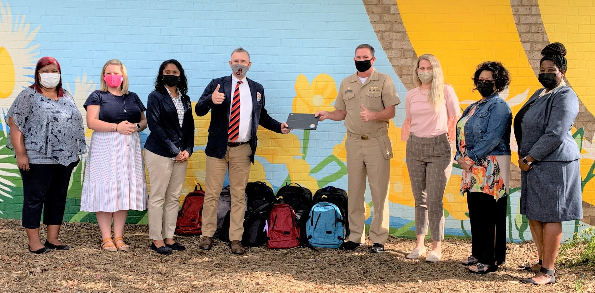 Naval Surface Warfare Center Dahlgren Division (NSWCDD) Commanding Officer Capt. Stephen “Casey” Plew presents 10 laptop computers and carrying cases donated by the warfare center to Fredericksburg City Public Schools (FCPS) officials. Pictured from left to right are Keesha Keels, Hugh Mercer Elementary School Assistant Principal, Kelsey Bolling, FCPS STEM and Gifted Education Teacher, Dr. Kecia Lipscomb, FCPS Director of Curriculum and Instruction, Dr. Matthew Eberhardt, FCPS Deputy Superintendent, NSWCDD Commanding Officer Capt. Plew, Courtney Wheeler, Lafayette Elementary School Principal, Lisa Lewis, Lafayette Elementary School STEM and Gifted Education Teacher and Tiffany Owens, NSWCDD STEM Lead.