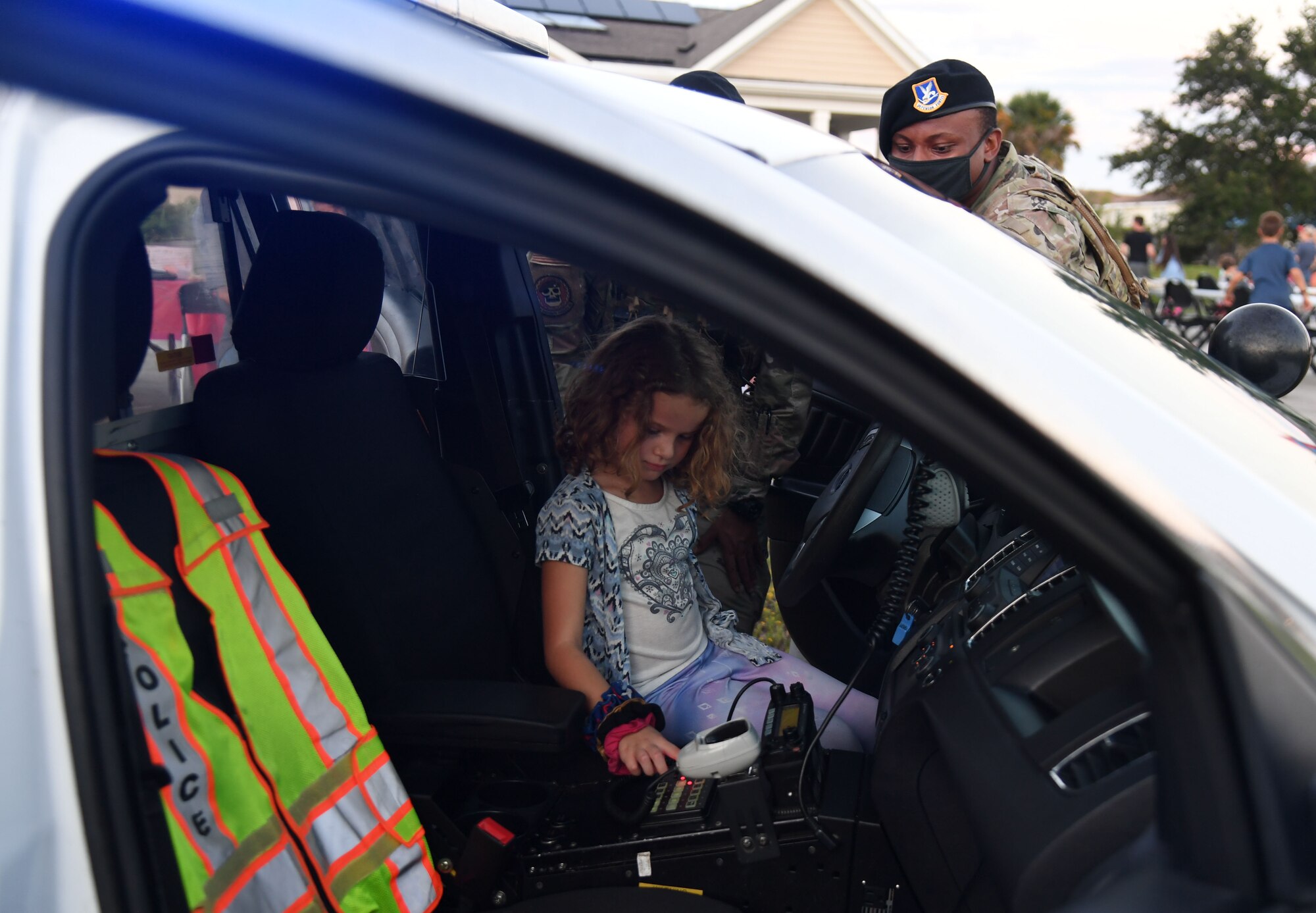 U.S. Air Force Airman Tyler Berry and Airman 1st Class Kaleb Brisbone, 81st Security Forces Squadron patrolmen, provide a patrol car tour to Madalynn Serabian, daughter of Maj. Christi Serabian, 81st Operational Medical Readiness Squadron mental health officer in charge, during the 81st SFS National Night Out at the Bay Ridge Community Center at Keesler Air Force Base, Mississippi, Oct. 5, 2021. The event, which was held to enhance the relationship between neighbors and law enforcement, also included a military working dog demonstration, scavenger hunt and train rides. (U.S. Air Force photo by Kemberly Groue)