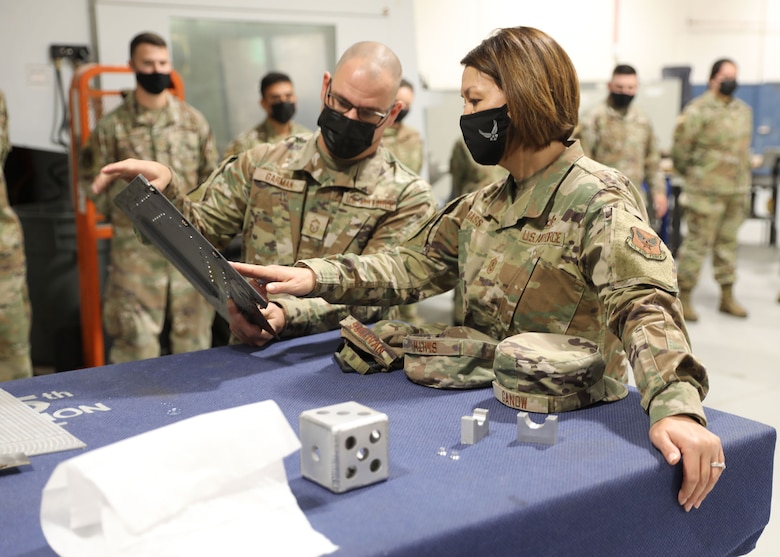 Senior Master Sgt. Nicholas Garman, 445th Maintenance Squadron fabrication flight superintendent, shows Chief Master Sgt. of the Air Force JoAnne Bass one of the fabricated parts his shop made during one of her stops as part of her visit to the 445th Airlift Wing Oct. 2, 2021.