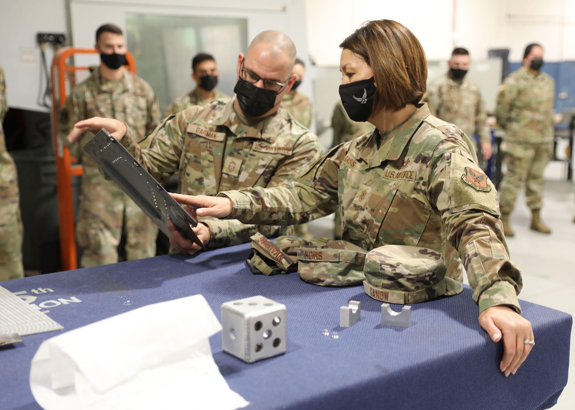 Senior Master Sgt. Nicholas Garman, 445th Maintenance Squadron fabrication flight superintendent, shows Chief Master Sgt. of the Air Force JoAnne S. Bass one of the fabricated parts his shop made during her visit to Wright-Patterson Air Force Base, Ohio, Oct. 2, 2021.