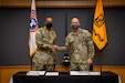 two men in army uniforms signing a memorandum on a table.