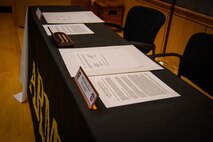 two men in army uniforms signing a memorandum on a table.